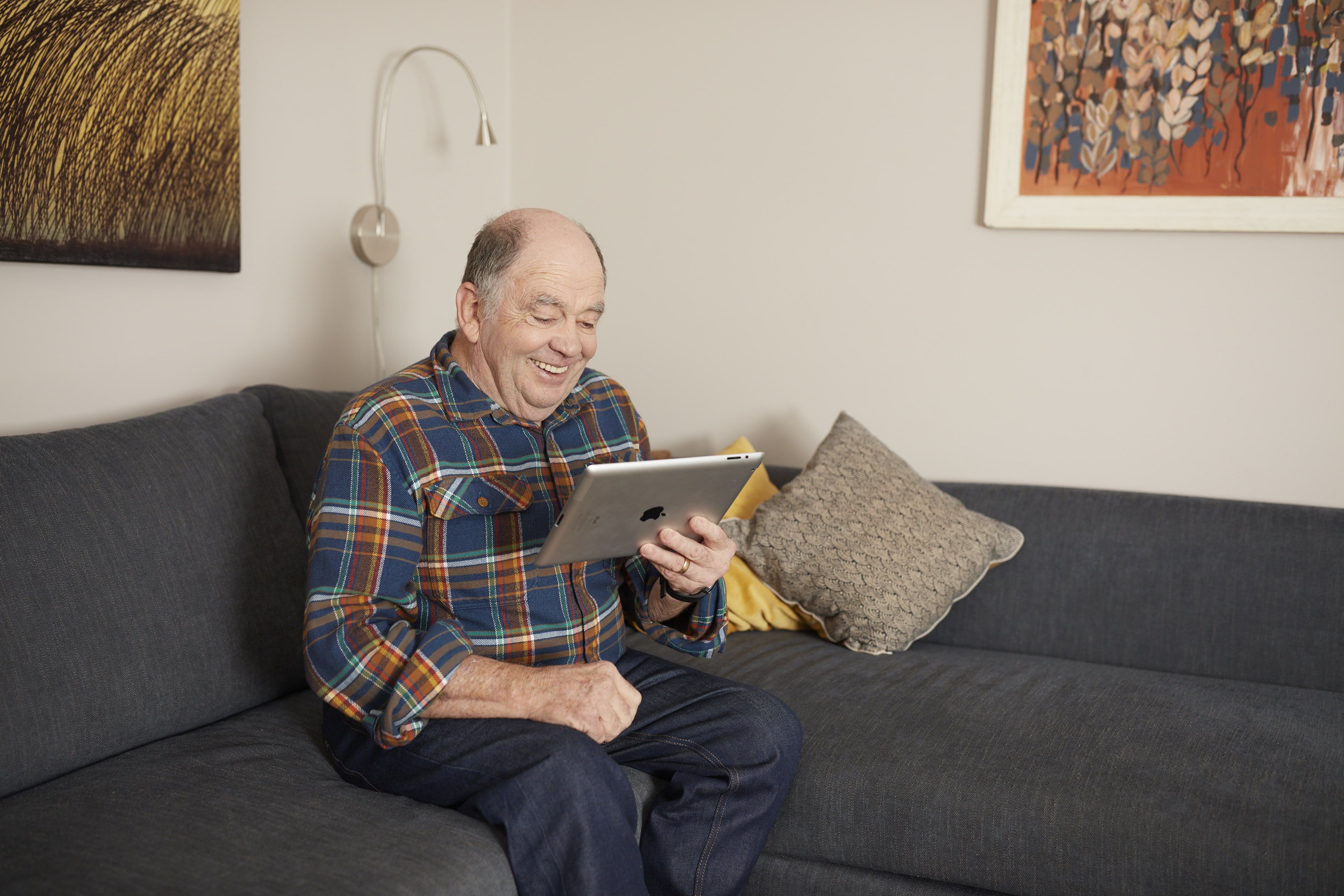 A man sits on the couch looks at his iPad