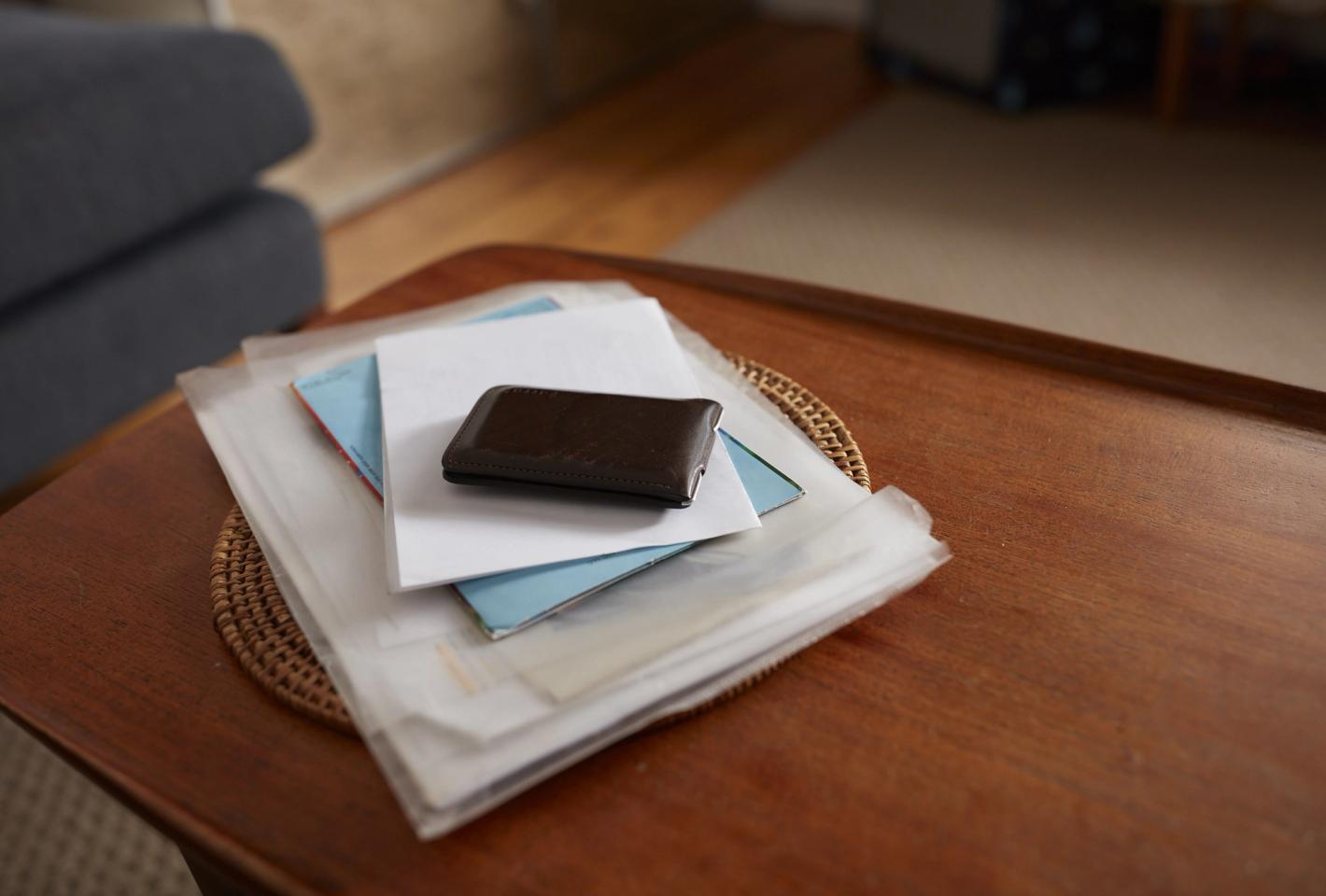 A wallet and a stack of papers on a coffee table
