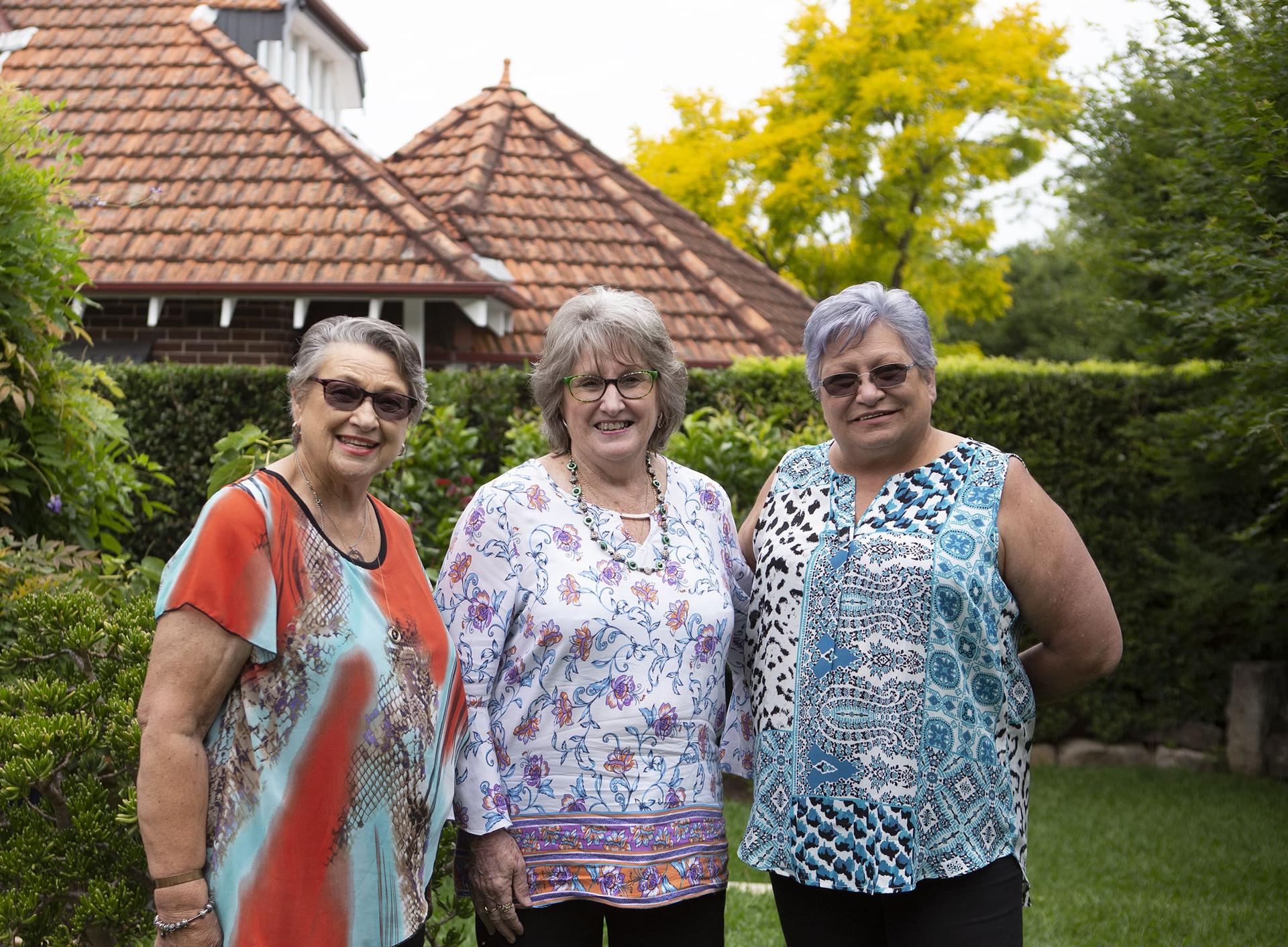 Household Capital customers Lynne, Raelene and Suzanne stand smiling to camera in a garden