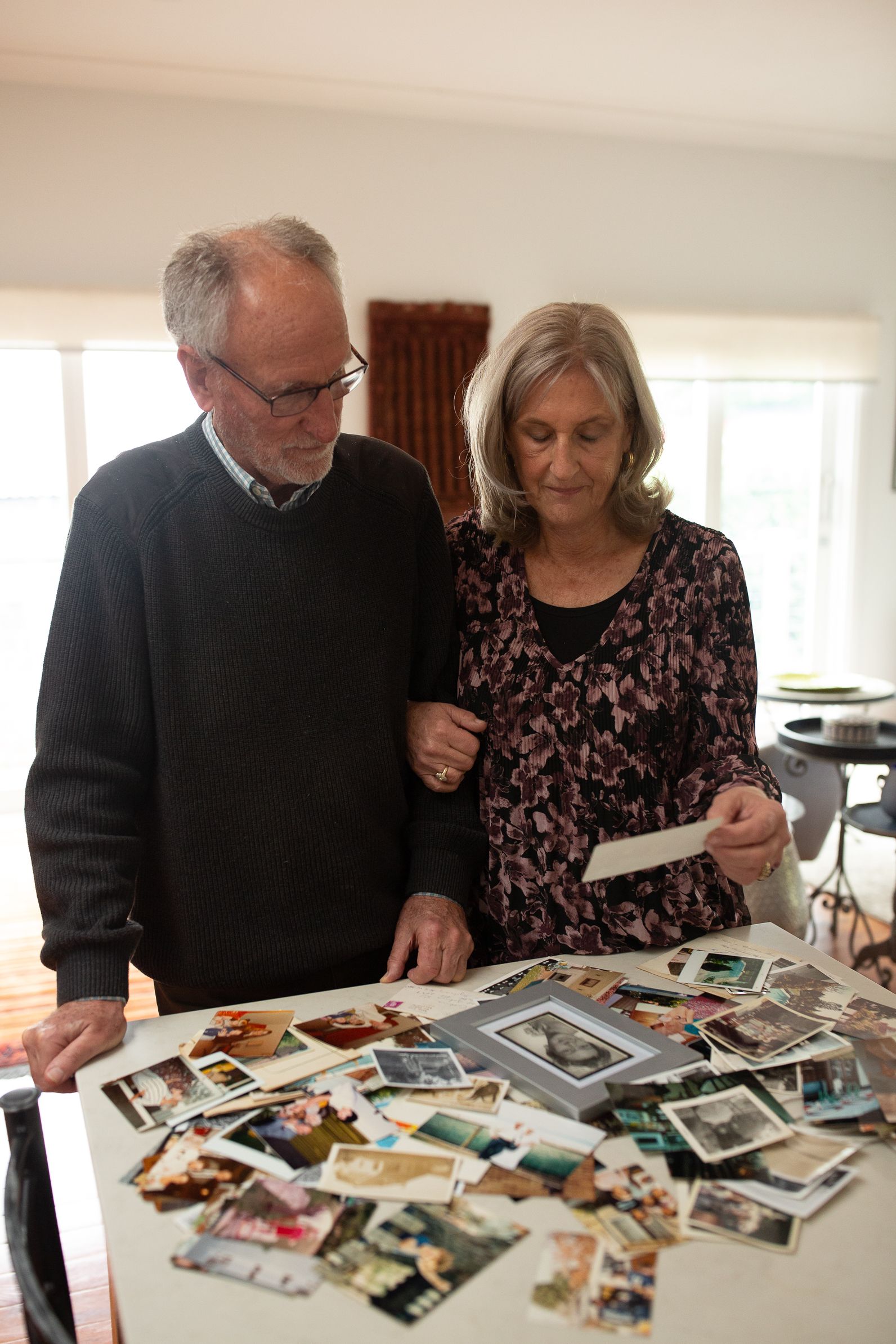 Couple standing by a table looking at photos