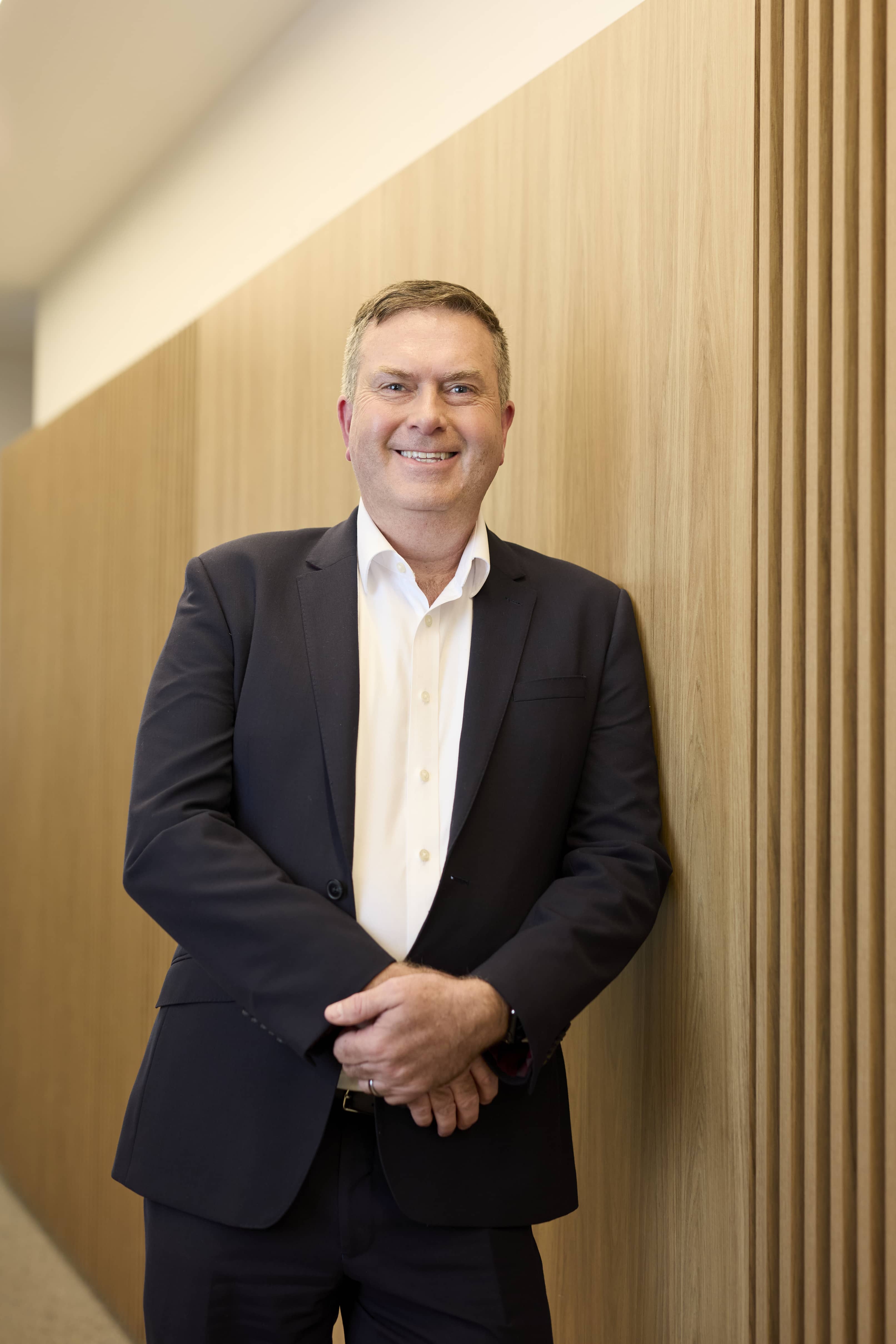 Man wearing a suit leaning against a wall