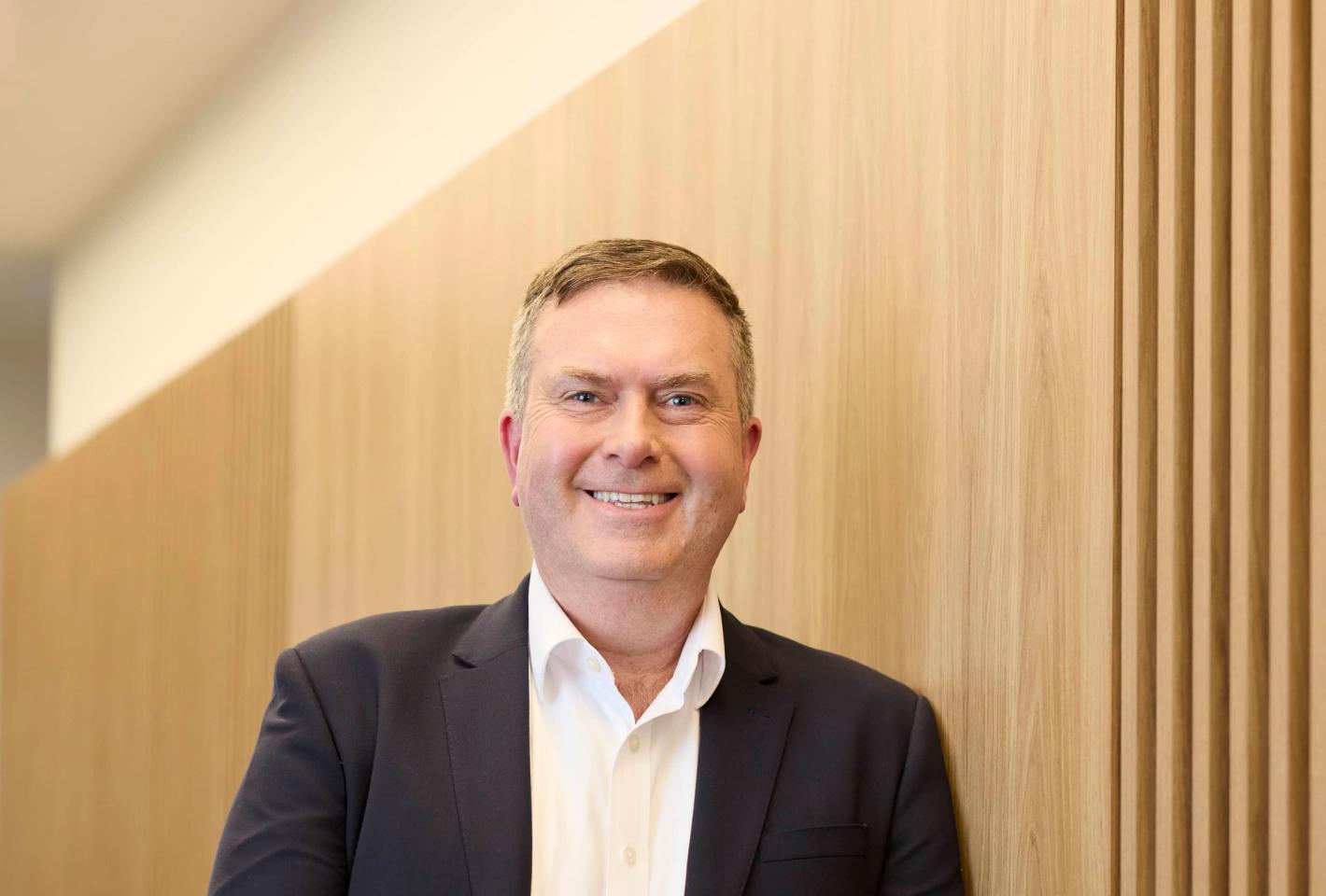 Man wearing a suit leaning against a wall