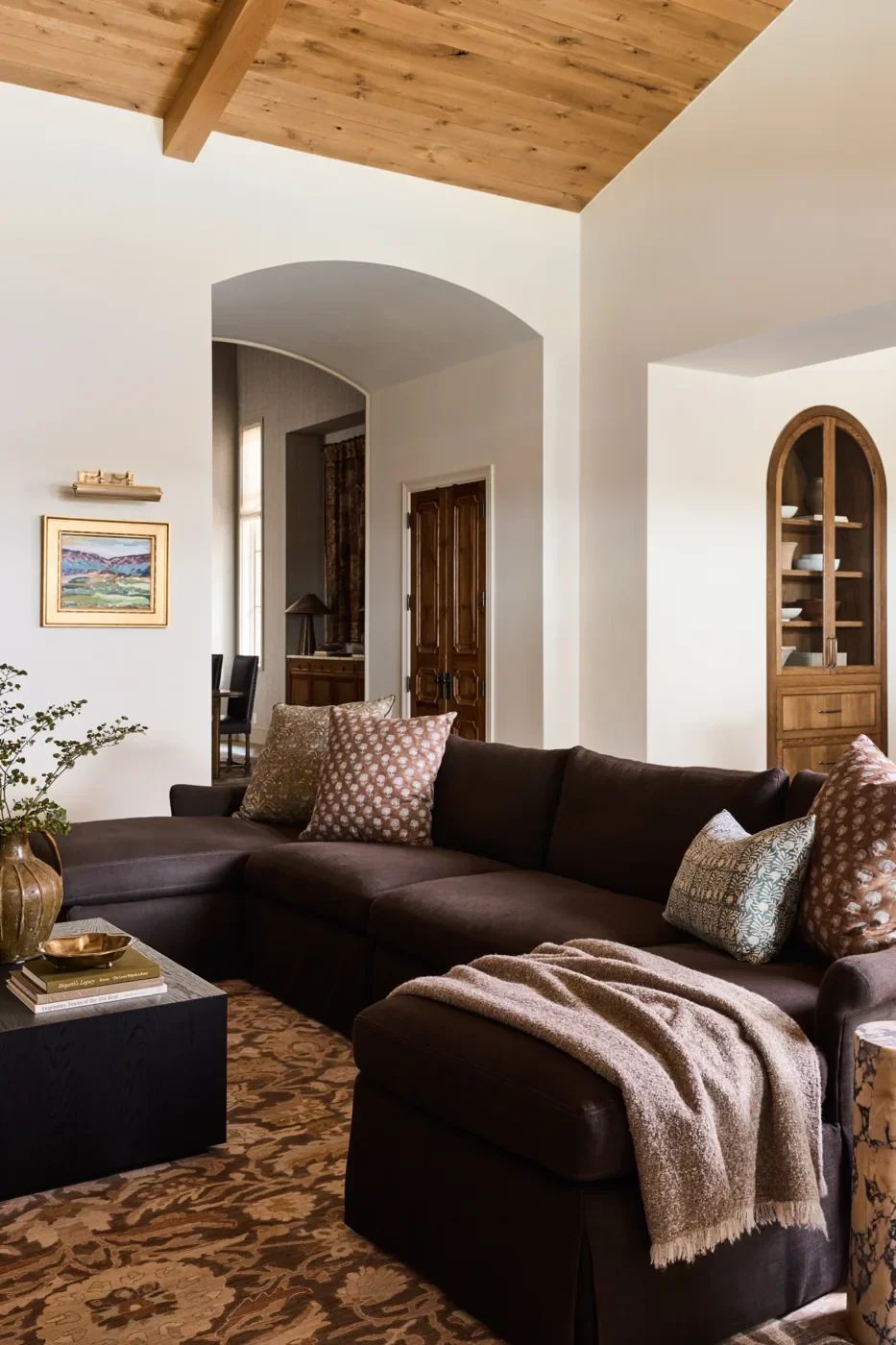 Living room with arched openings, wood cabinetry, and upholstered seating