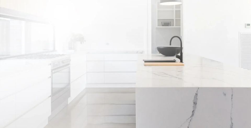 A bright white kitchen featuring elegant marble countertops and modern cabinetry.