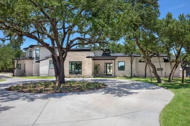 Contemporary home exterior with mature trees and a circular drive