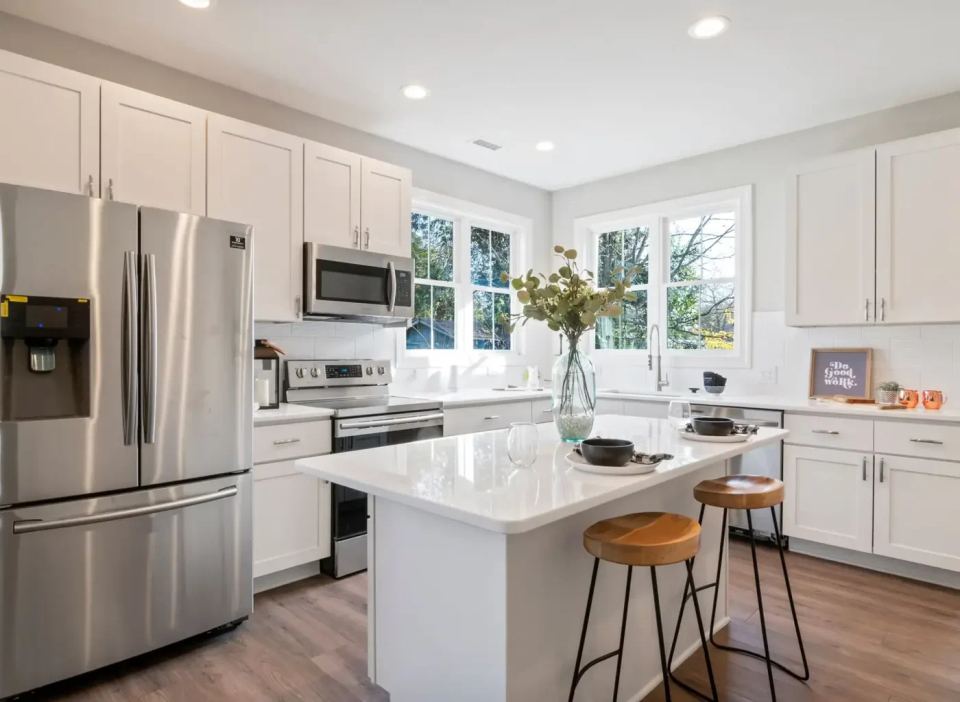 Bright remodeled kitchen with white shaker cabinets, a quartz island and stainless appliances