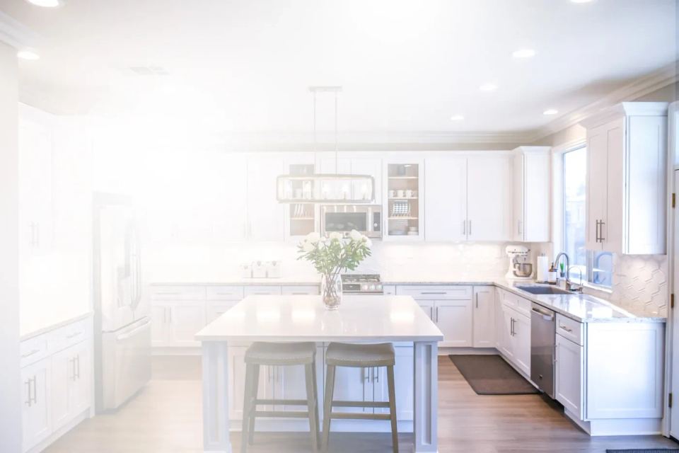 A modern kitchen featuring white cabinets and a spacious center island for cooking and dining.
