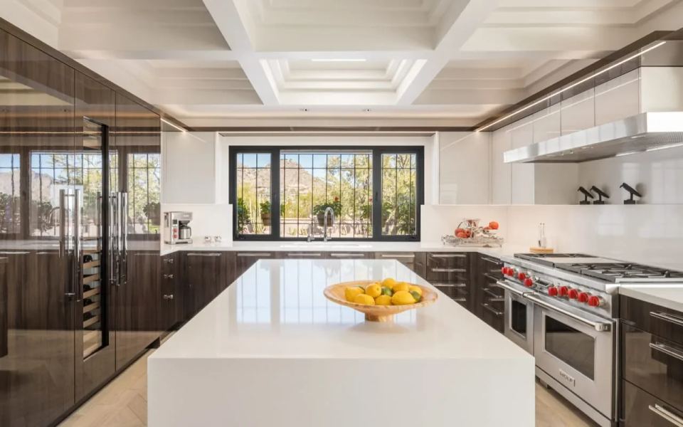 Contemporary ranch-style kitchen with glossy dark brown wood cabinetry. The kitchen has white coffered ceilings.