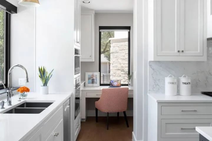 White kitchen with a built-in desk and garden-facing windows