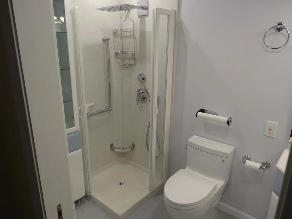 Finished bathroom with a tiled shower and glass enclosure