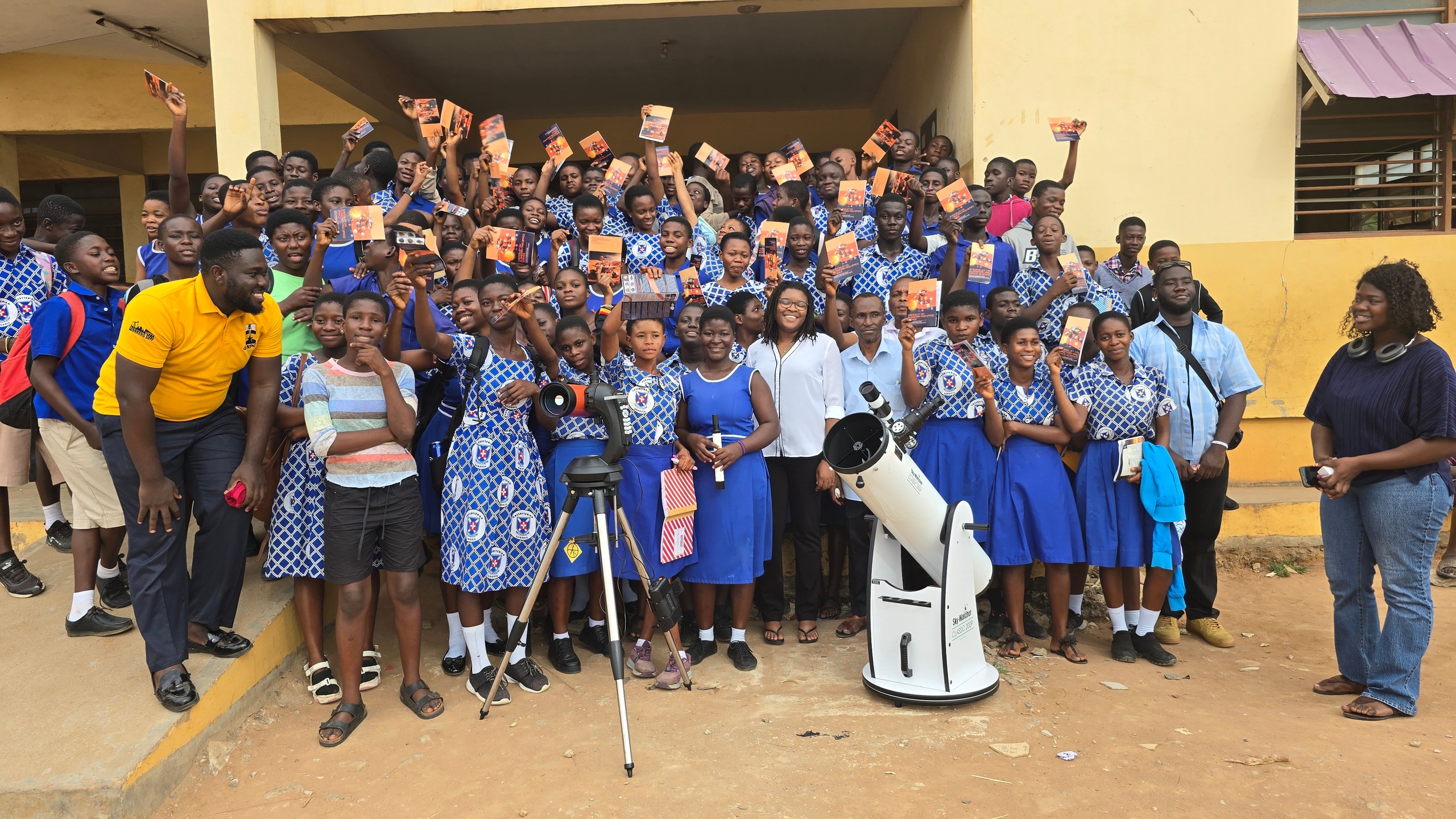 A school group poses with their telescope after a daytime observation session.