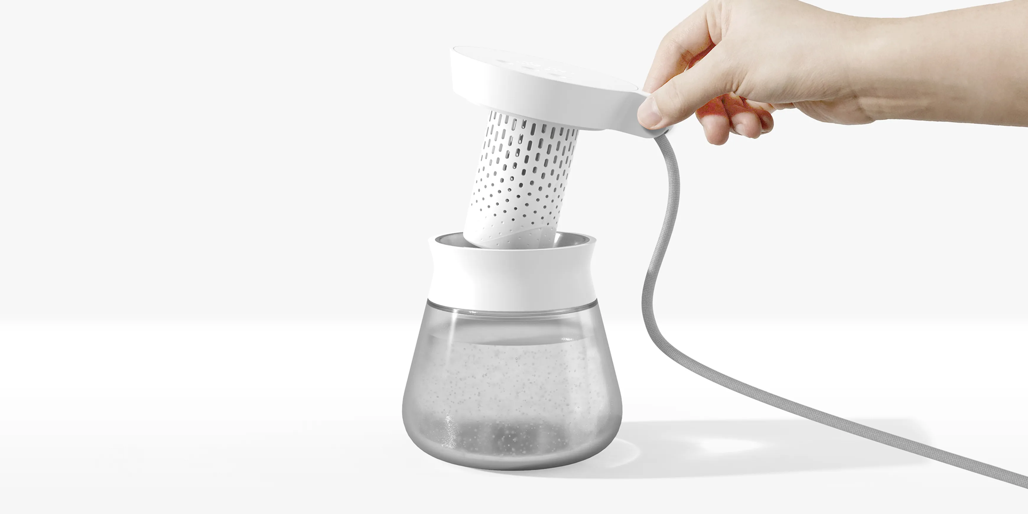 A hand reaching in to take of the heating element of the Intoku smart water kettle