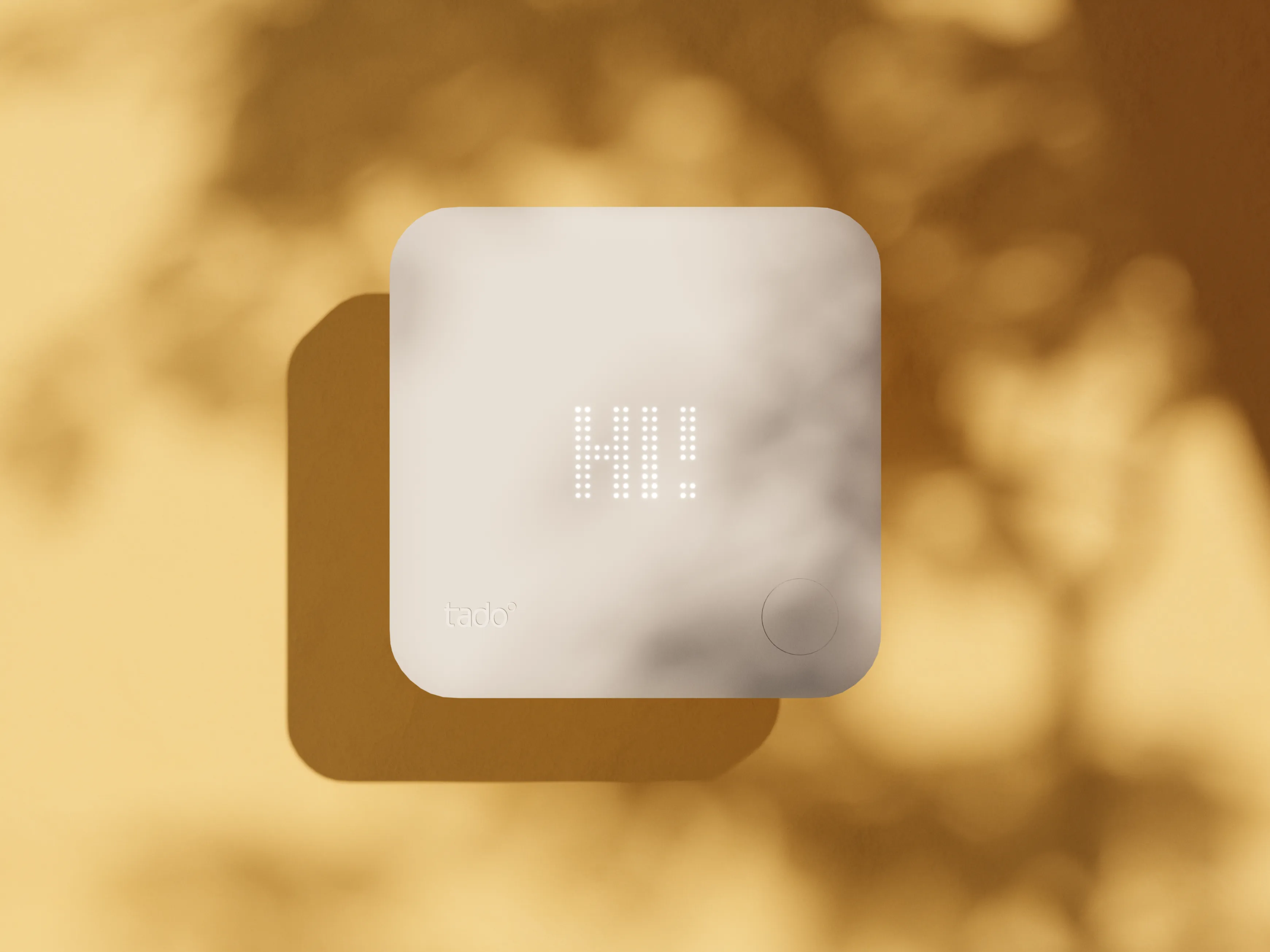The tado smart thermostat floating in front of a yellow wall