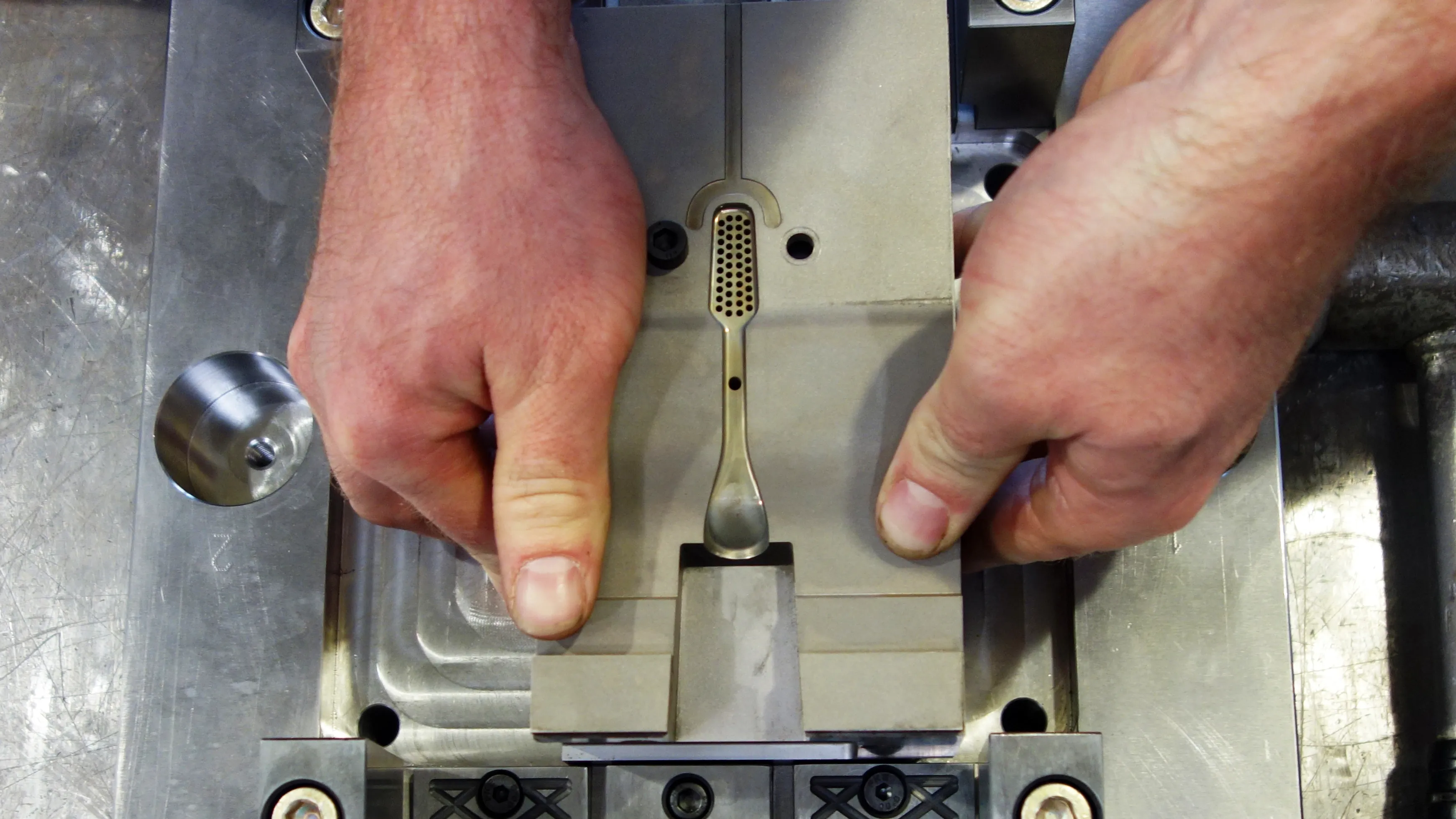 Hands holding the injection molding tool for a TIO toothbrush
