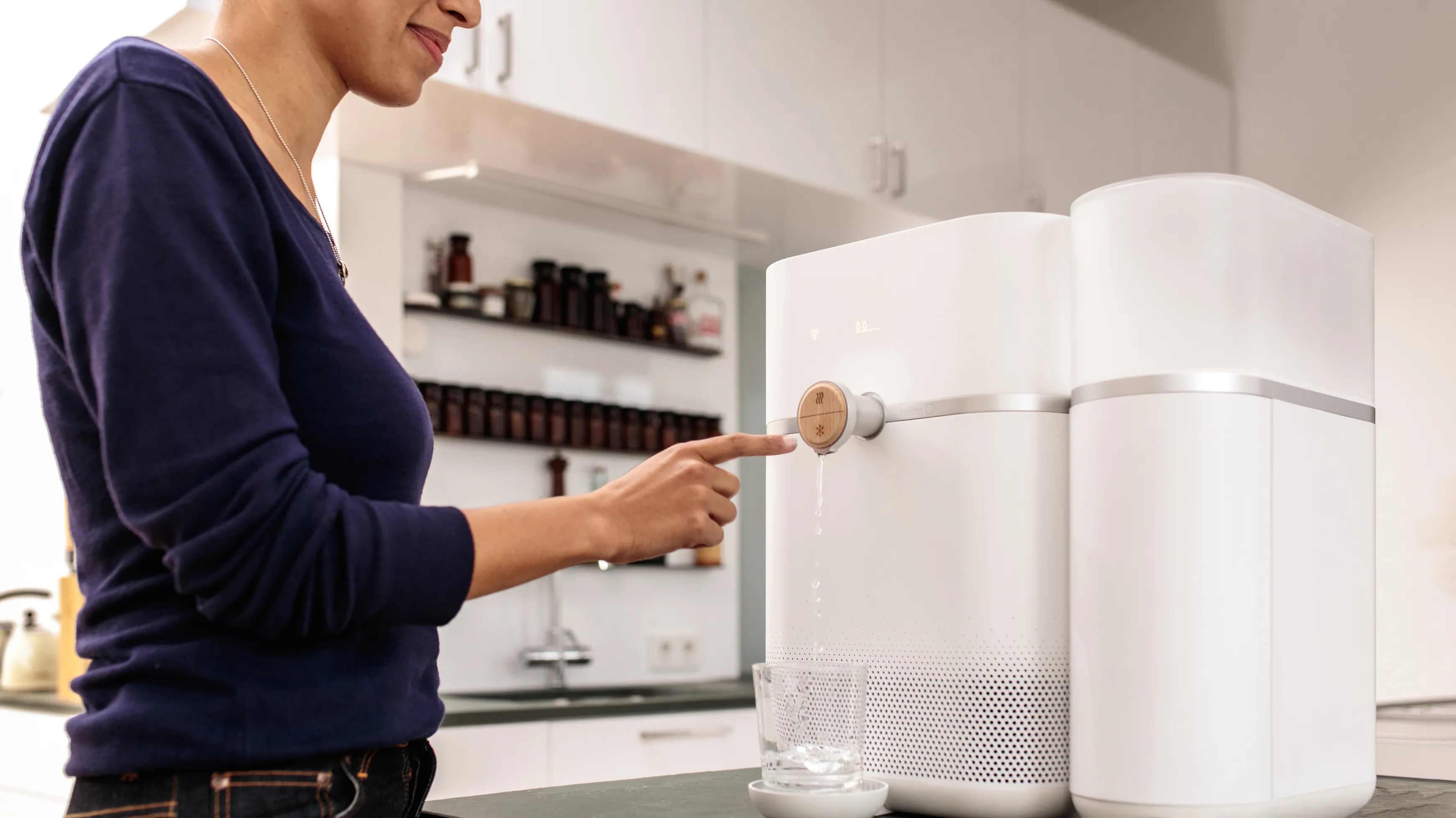 A woman interacting with the Mitte water purifier with a water glass