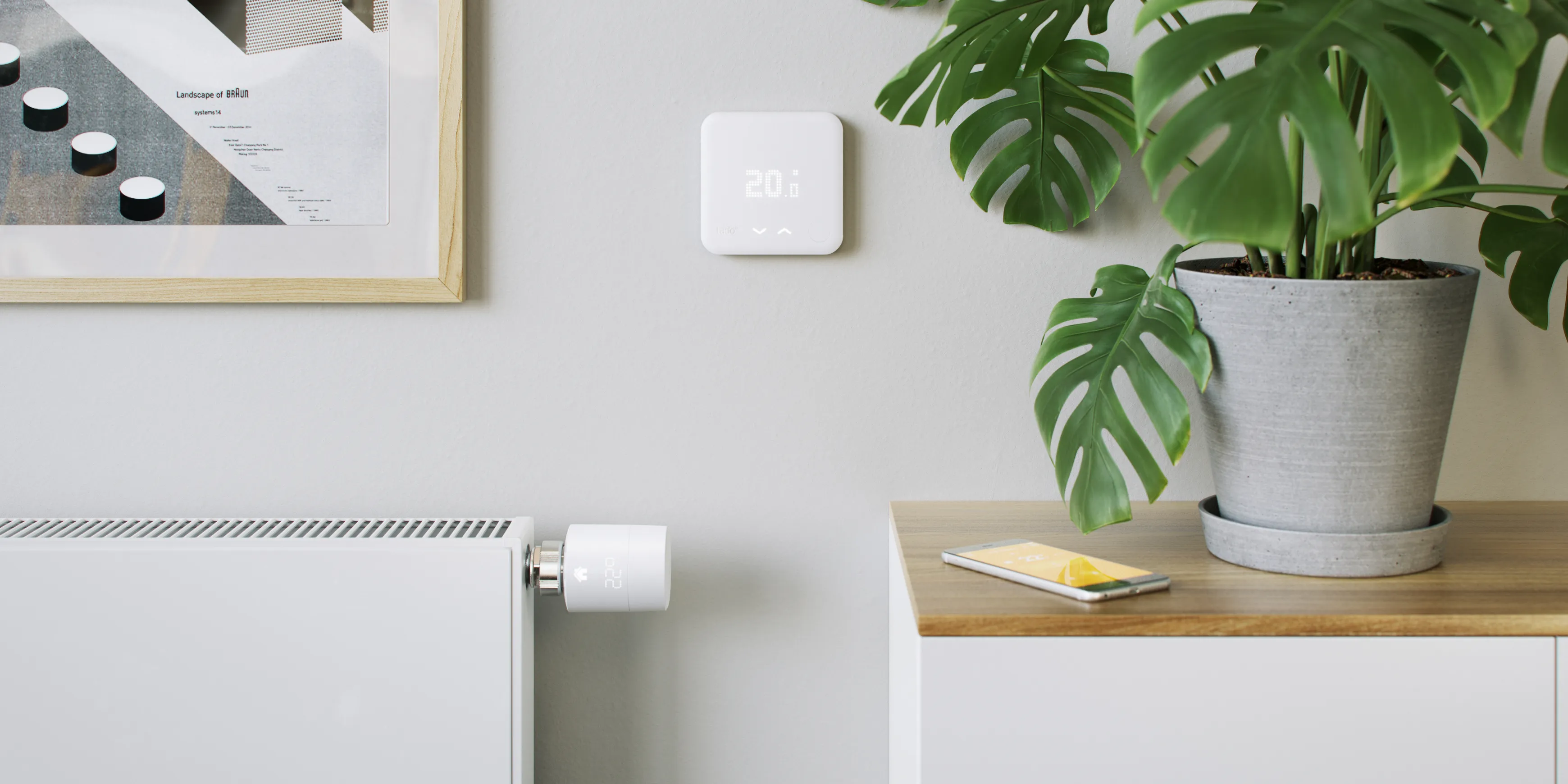 A tado smart heating radiator thermostat on a radiator next to a smart thermostat on a wall