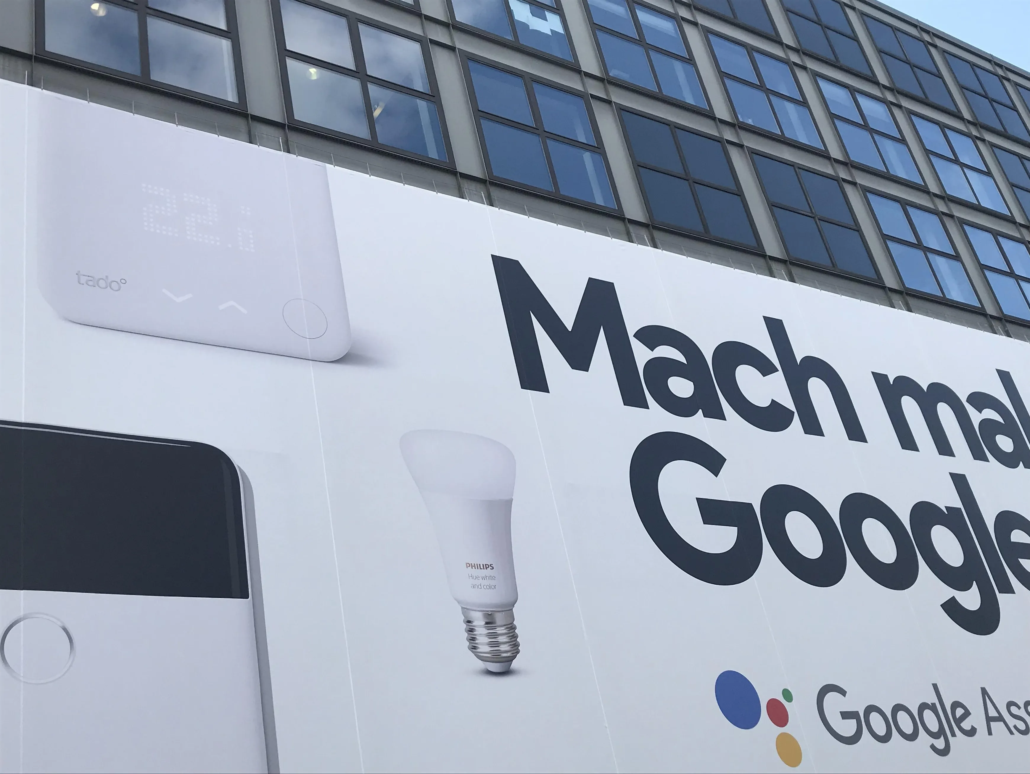 A tado smart thermostat on a big wall ad next to philips and google products