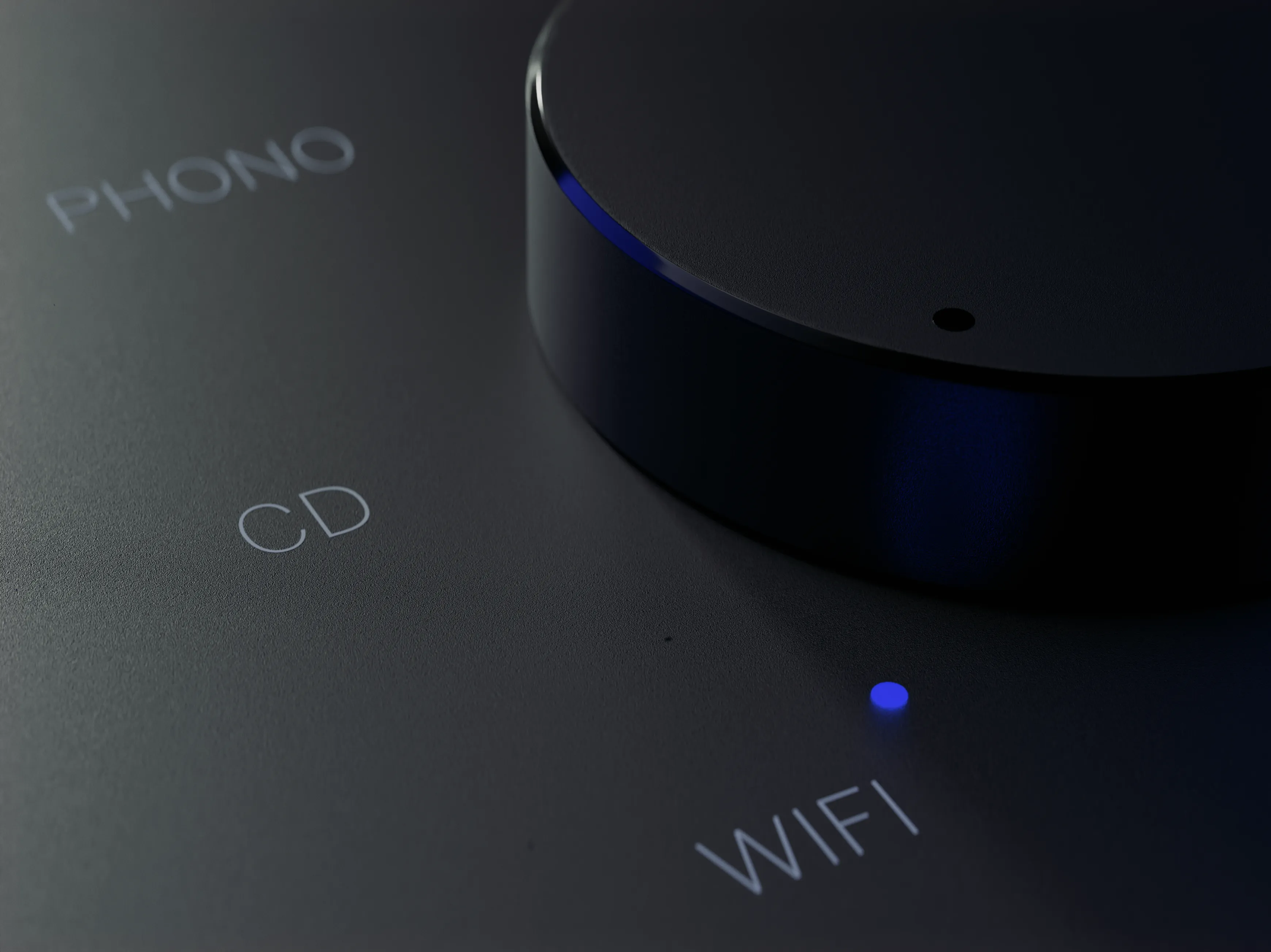 A closeup of a glowing button on a loewe music player