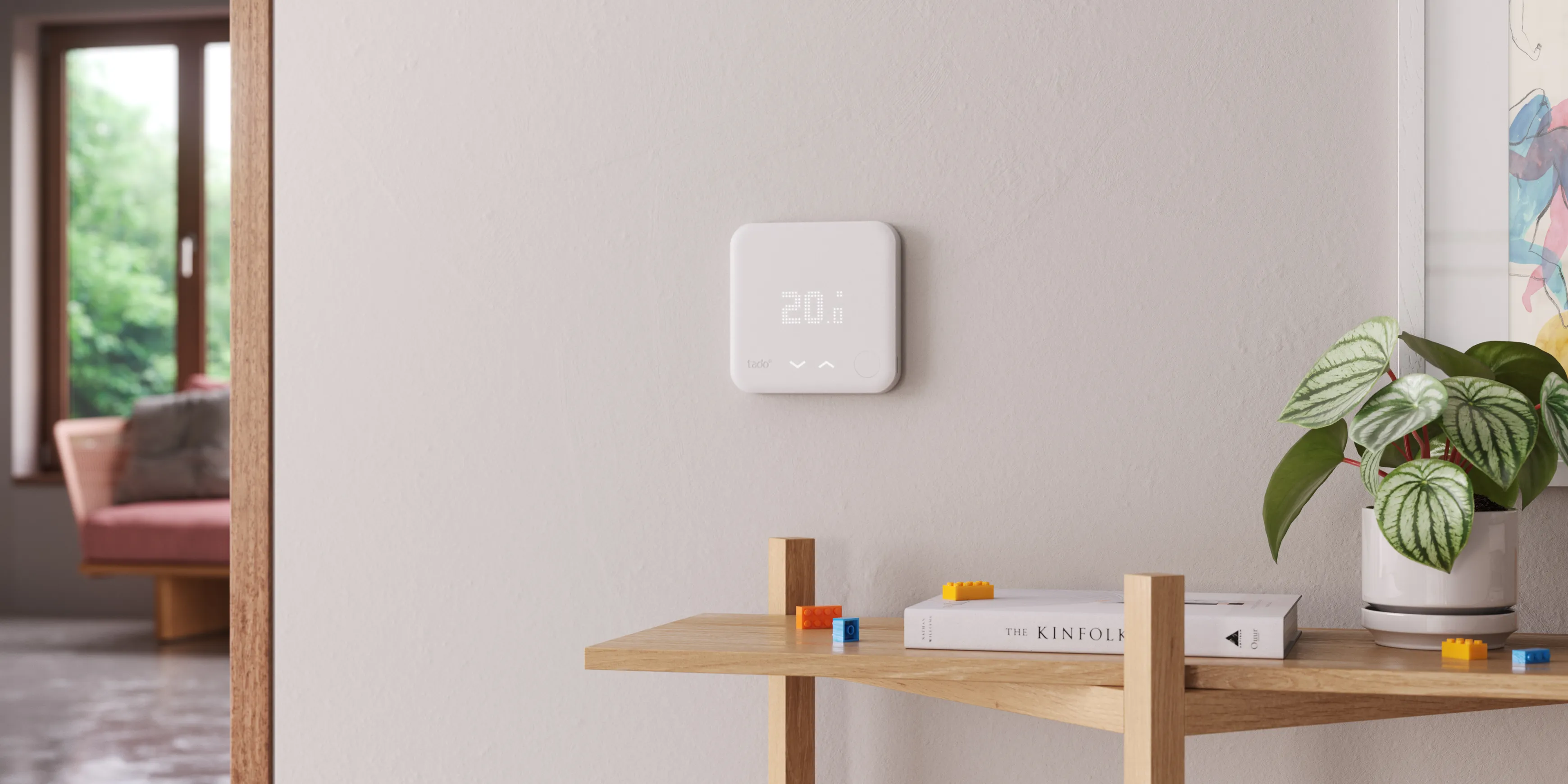 A tado smart thermostat on a wall in front of a wooden shelf