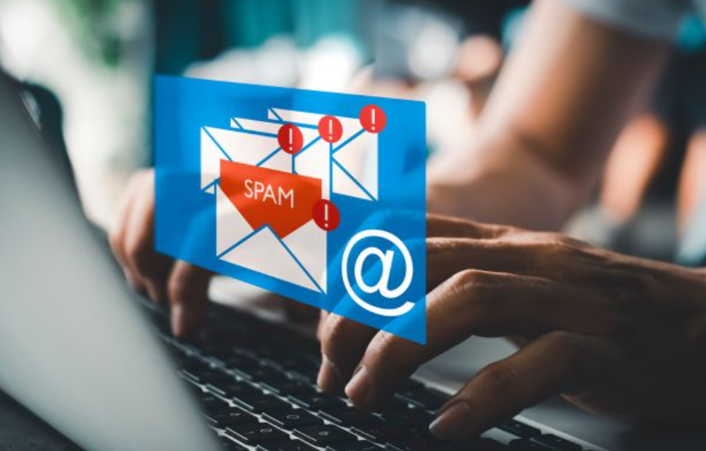 Image of a person working on a laptop with graphics representing spam emails.