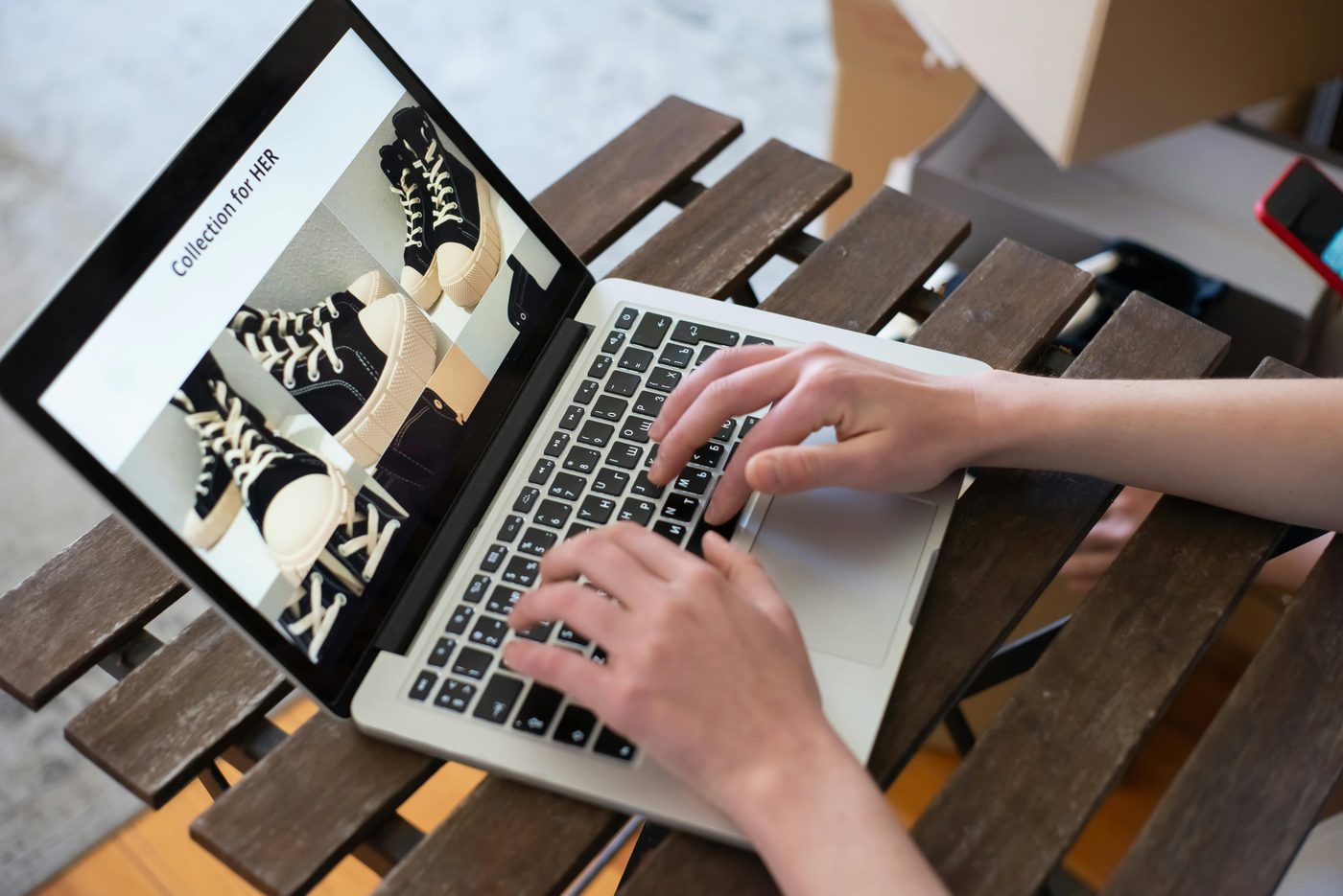 A person working on a laptop displaying a landing page with images of shoes.