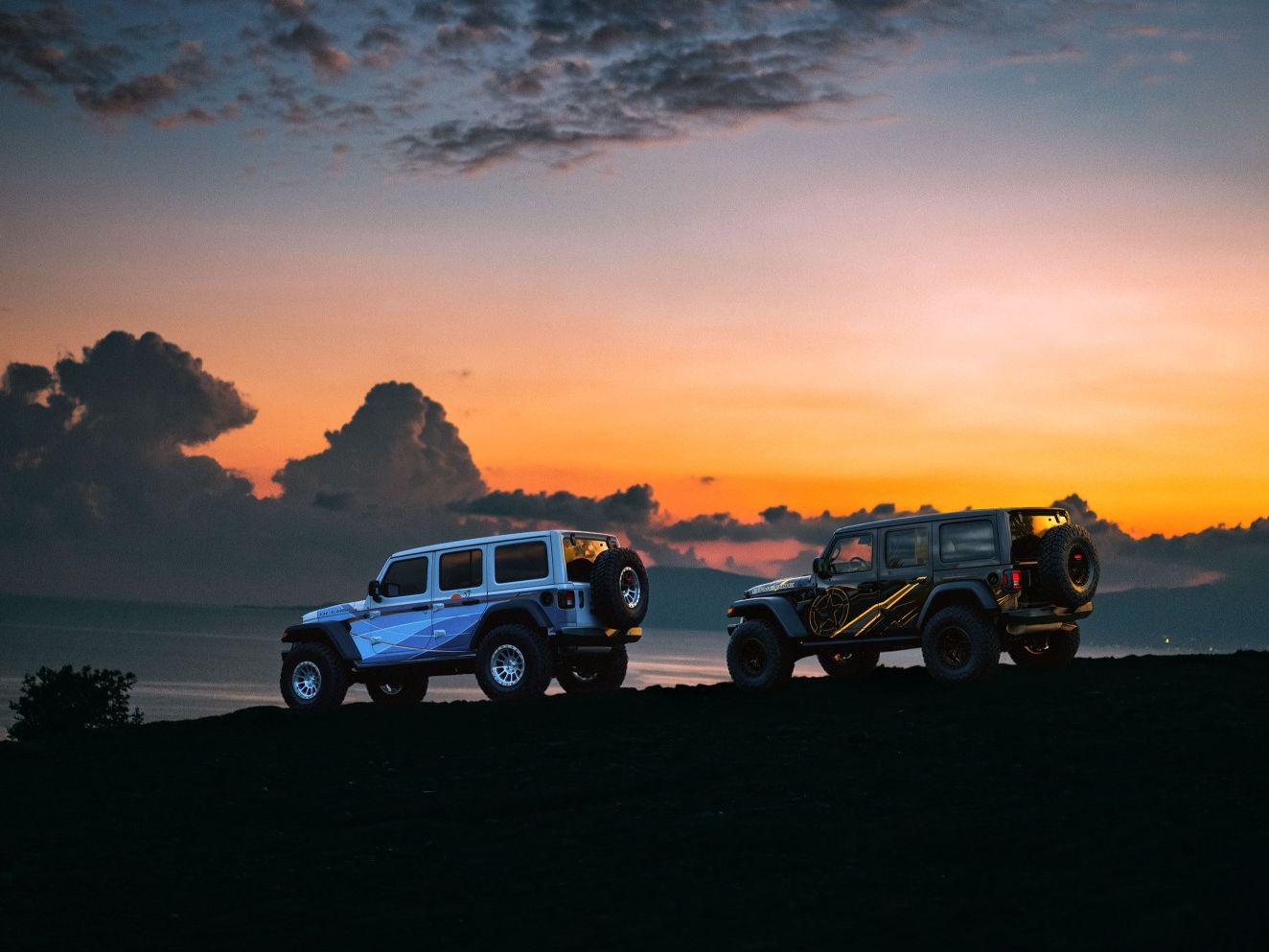 two jeep wranglers are parked on top of a hill at sunset .