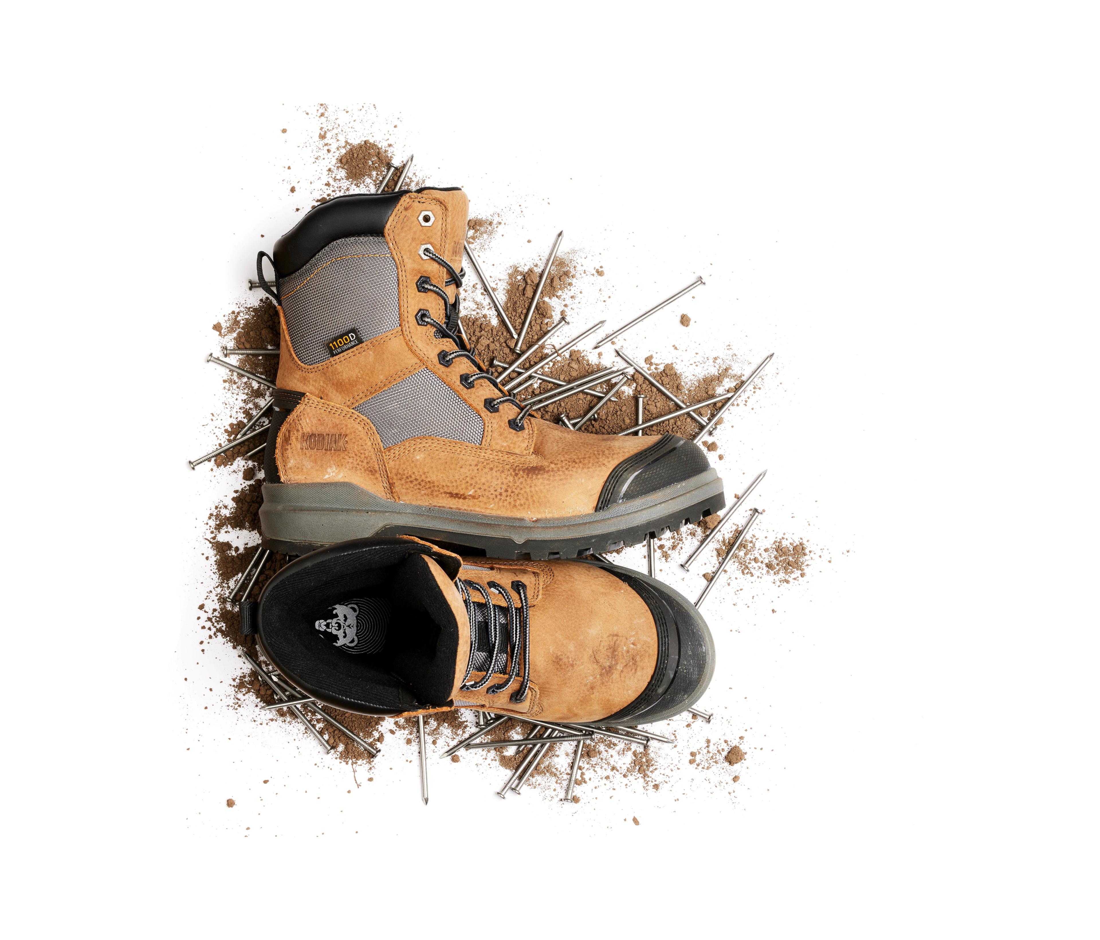 kodiak tan work boots with nails in the background covered in dirt