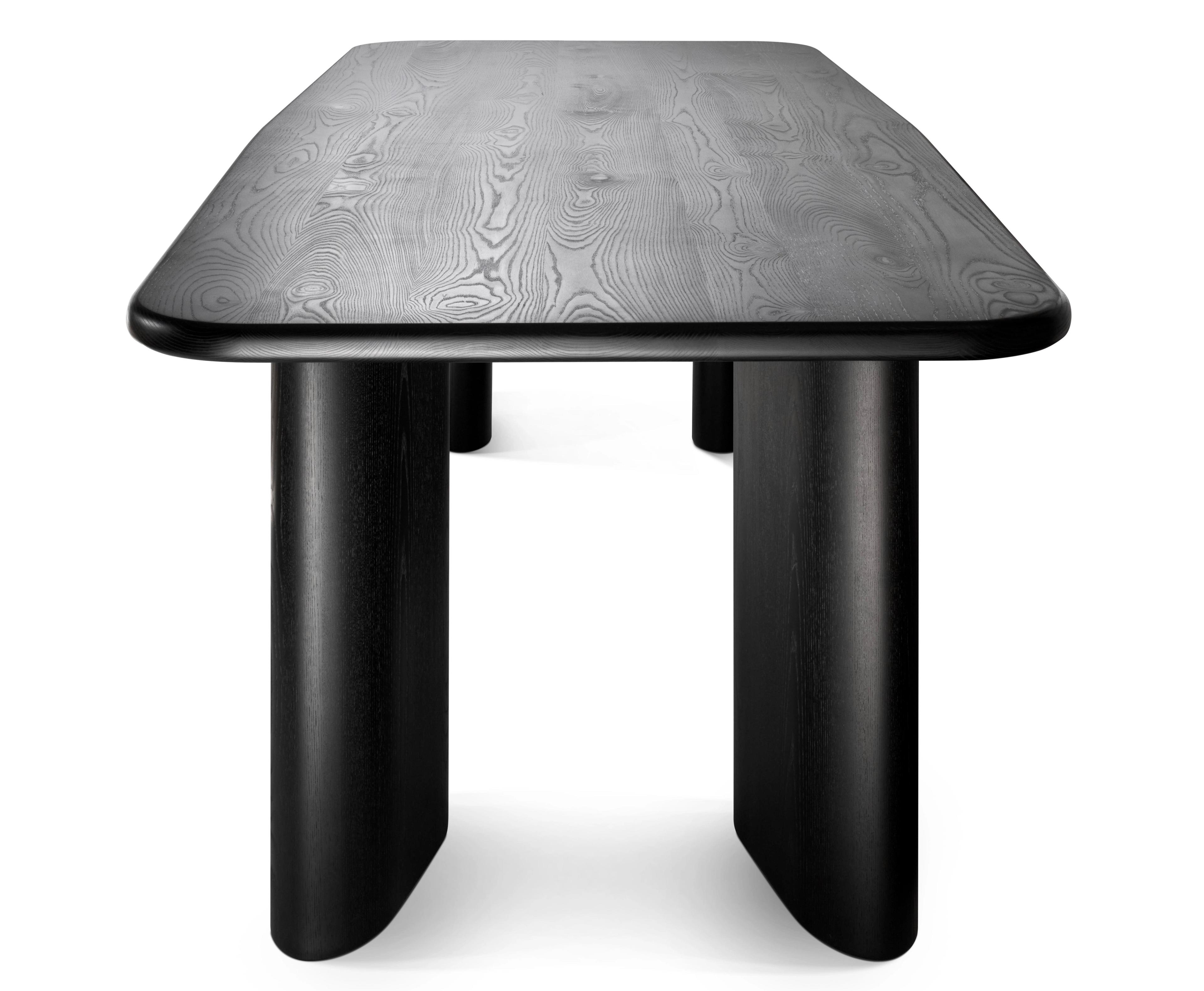 black oak dining table sculptural legs end view on white background photo
