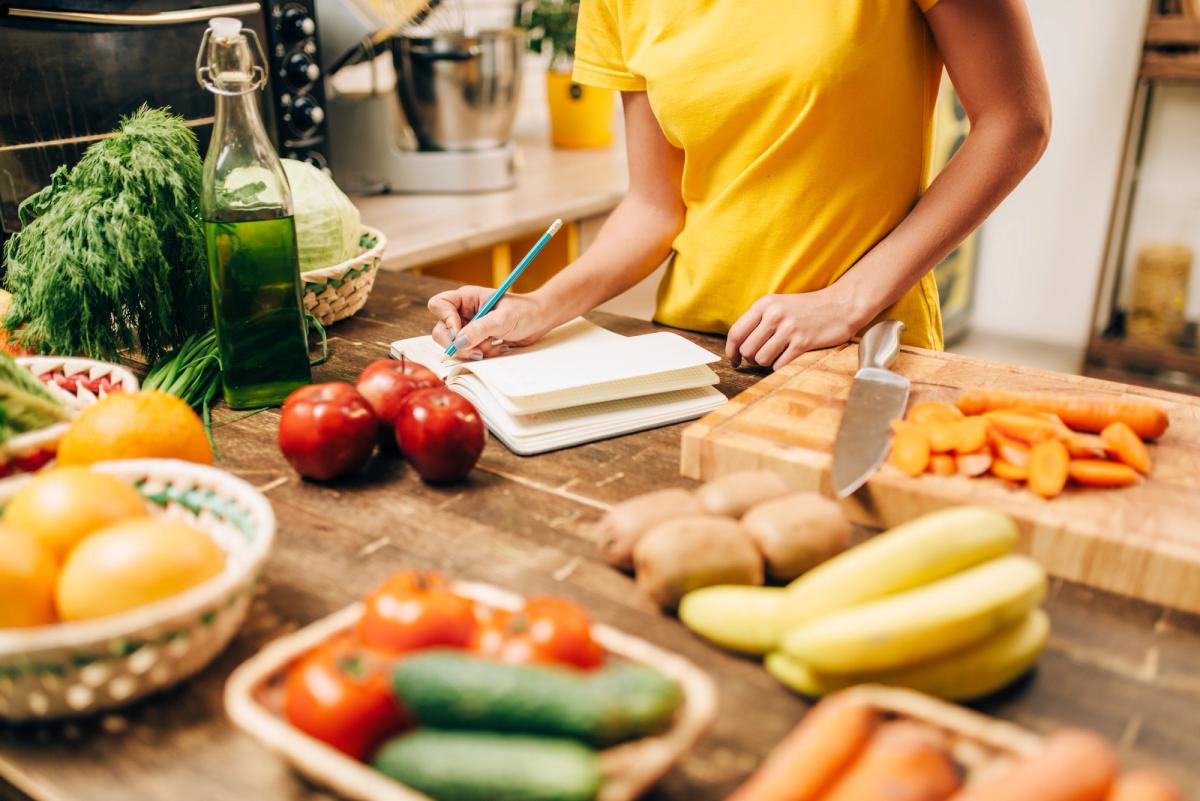 A person surrounded with veggies, writing in a notebook