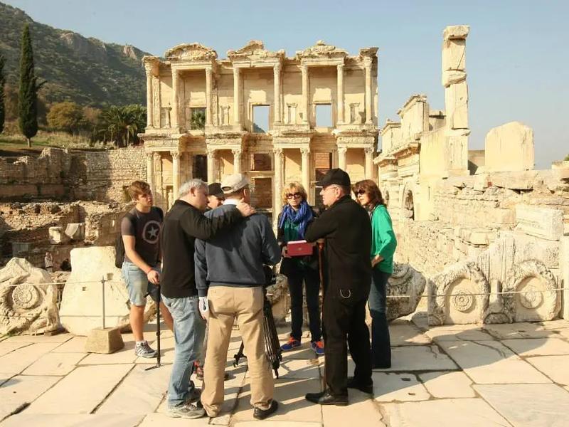 A private guide explaining the history of the Library of Celsus to a small group in front of its façade