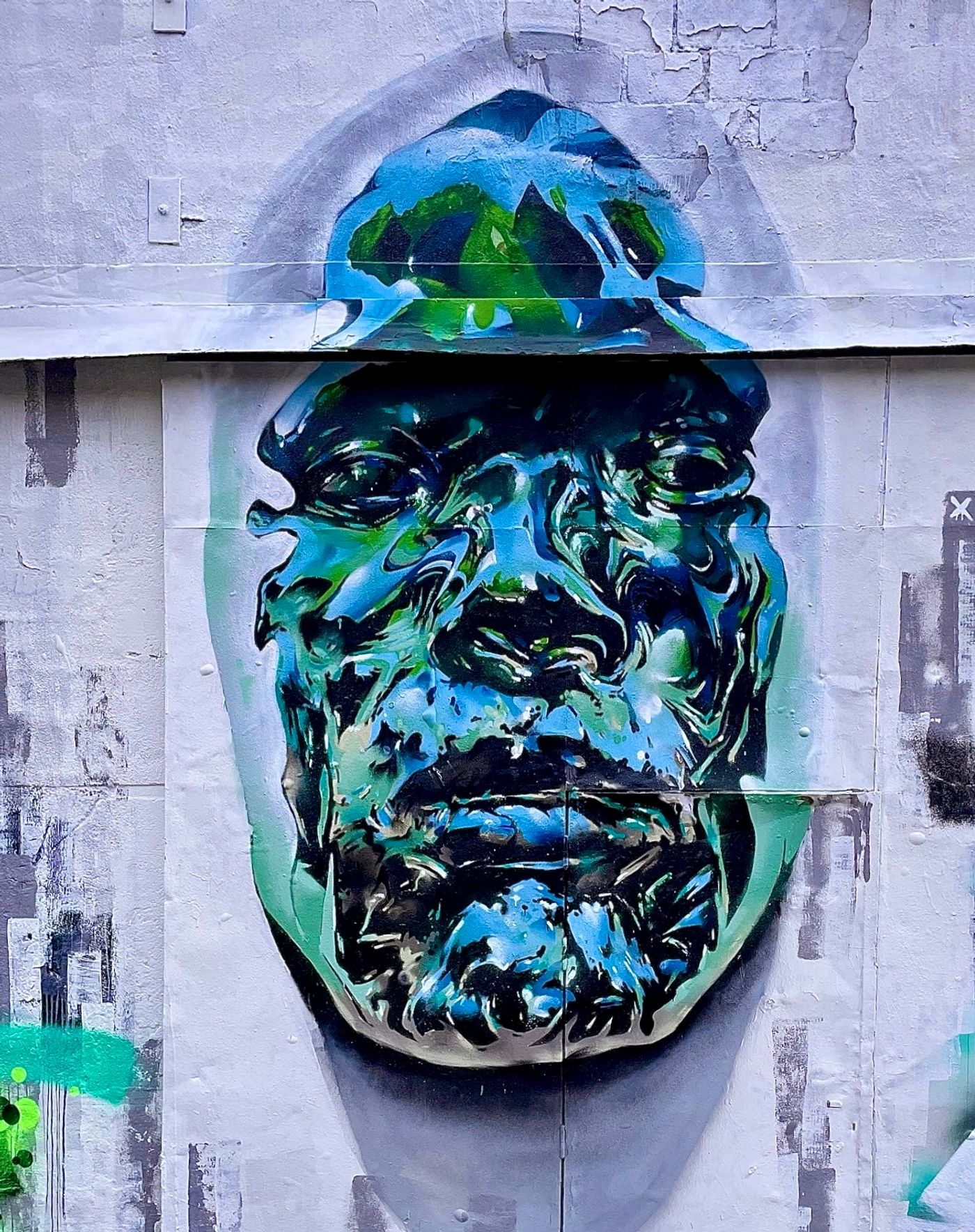 Realistiskt kromansikte som växer fram ur väggen, en studie i kromeffekt med sprayfärg av Spraya på Springbeast i Snösätra. Realistic chrome face emerging from a wall, a spray paint chrome effect study by Spraya at Springbeast in Snösätra.