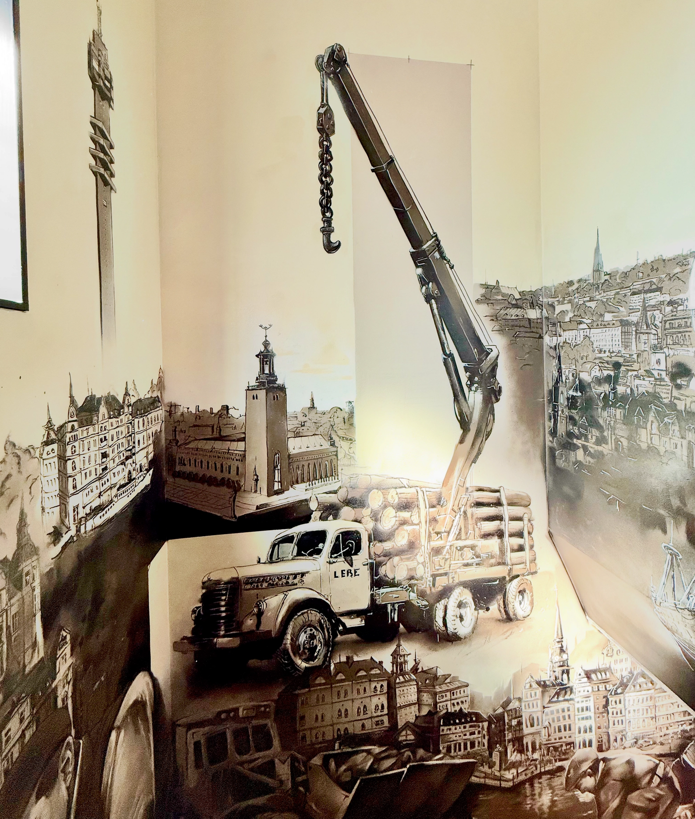 Hörn i trapphuset med en målad lyftkran, timmerbil och Stockholmssiluett i sepiatoner. Stairwell corner with a painted crane, timber truck and Stockholm skyline in sepia tones.