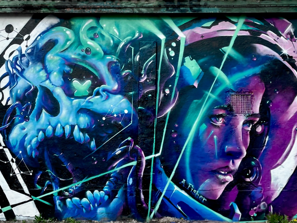 Graffitimålning i Snösätra av en blå dödskalle med tentakler bredvid en kvinnlig astronaut, en hyllning till Anna Lee Fisher. Graffiti mural in Snösätra of a blue skull with tentacles beside a female astronaut, a tribute to Anna Lee Fisher.
