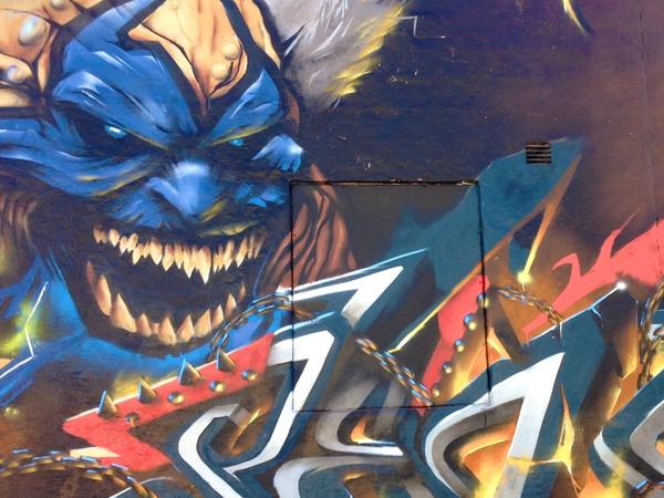 Graffitivägg i Snösätra med en flinande Violator ur Spawn-serien, brinnande graffitibokstäver och kedjor, målad på Springbeast 2014. Graffiti wall in Snösätra with a grinning Violator from the Spawn comics, burning graffiti letters and chains, painted at Springbeast 2014.