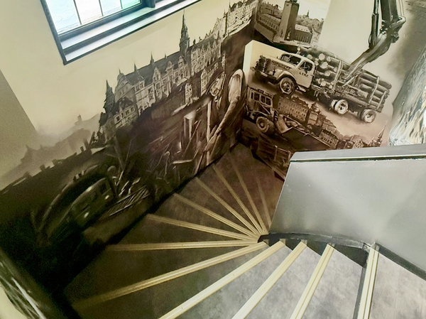 Trapphus hos XL Bygg Lebe i Tyresö med en sepiafärgad väggmålning av historiska Stockholmsbyggnader och byggscener, av Spraya. Stairwell at XL Bygg Lebe in Tyresö painted with a sepia mural of historic Stockholm buildings and construction scenes, by Spraya.