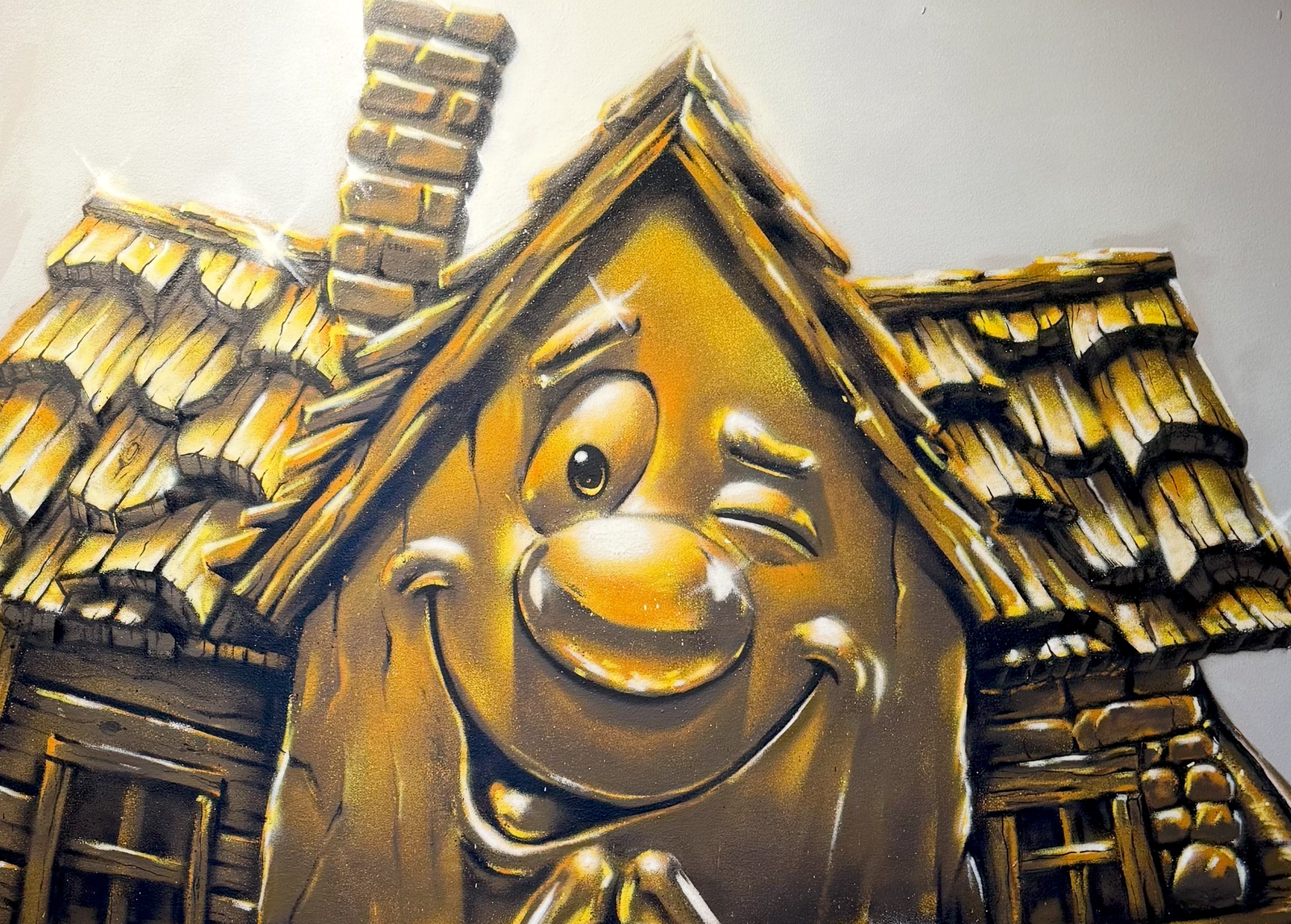 Spotlight på den gyllene Lebe-maskoten, ett leende hus med knäppta händer, handmålad i fotorealistiskt guld hos XL Bygg Lebe i Tyresö. Spotlit golden Lebe mascot, a smiling house with clasped hands, hand-painted in photorealistic gold at XL Bygg Lebe in Tyresö.