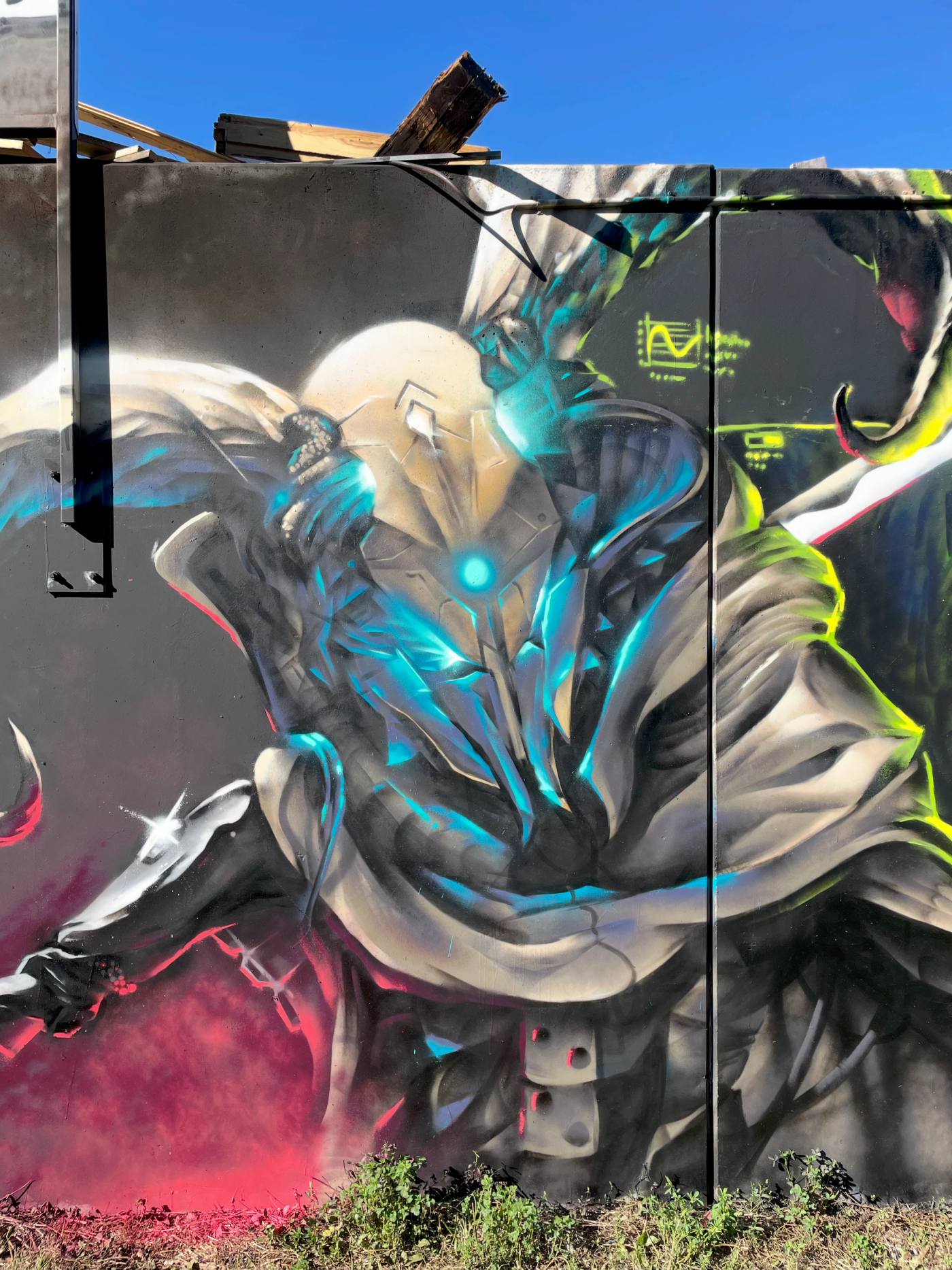 Sci-fi-graffitimålning i Visby av Spraya: en mantelklädd utomjording med lysande blått ansikte och spjut, ur The Raukonium Saga. Sci-fi graffiti mural in Visby by Spraya: a cloaked alien council member with a glowing blue face and a spear, from The Raukonium Saga.