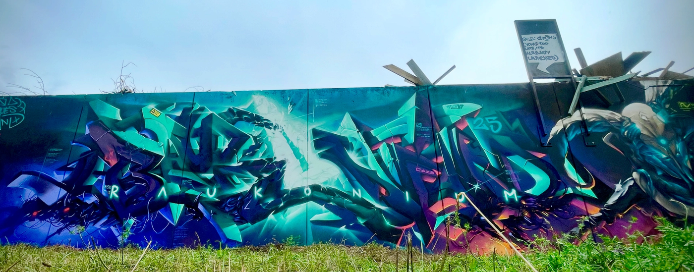 Kapitel 4 av The Raukonium Saga i Visby, sett över en gräsyta. Wide view of chapter 4 of The Raukonium Saga mural in Visby above a grass field.
