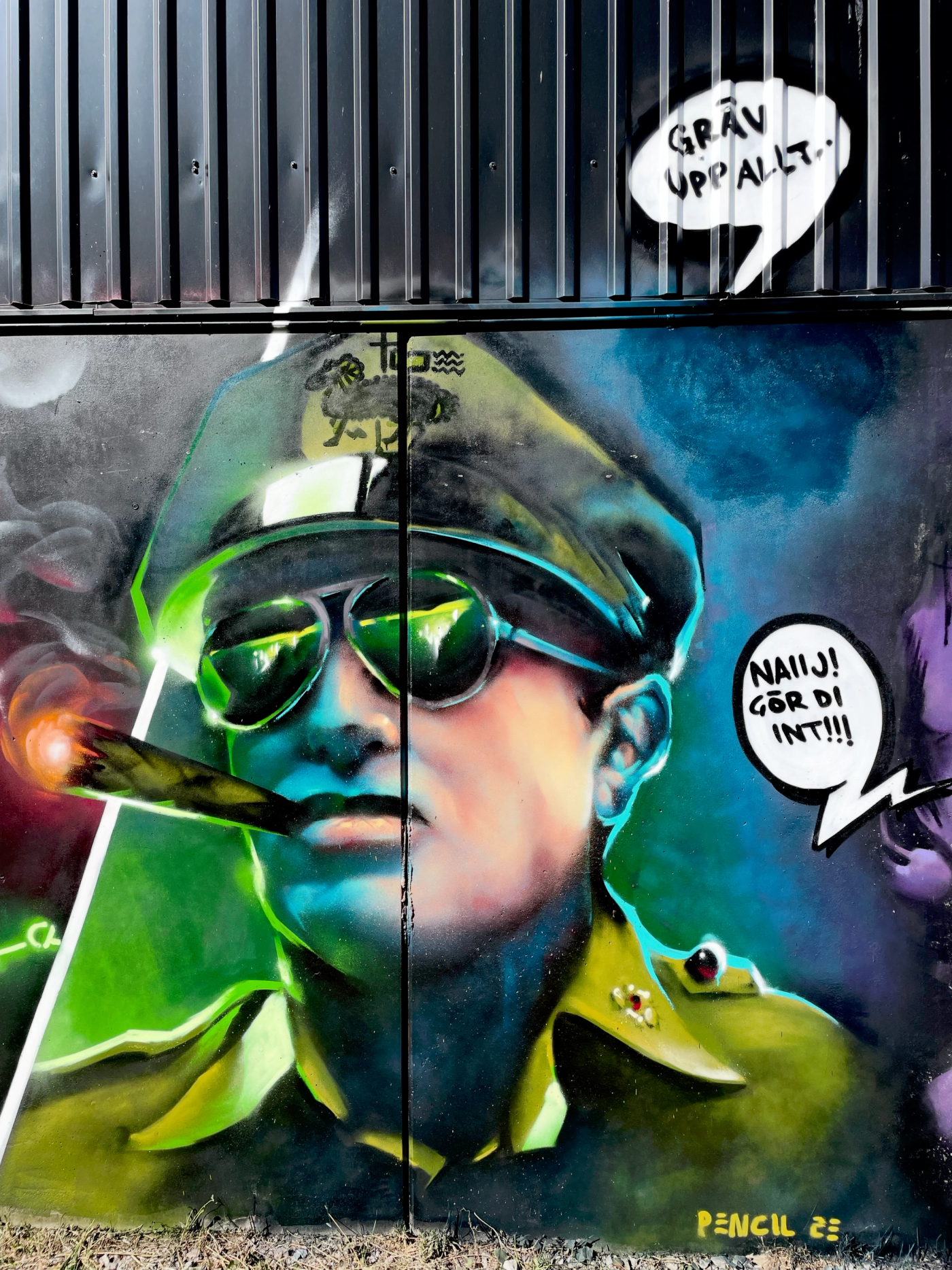 Spraymålat porträtt av en gotländsk armégeneral med pilotglasögon, cigarr och pratbubblor på gotländska. Spray-painted portrait of a Gotland army general in aviator sunglasses with a cigar and speech bubbles in Gotland dialect.