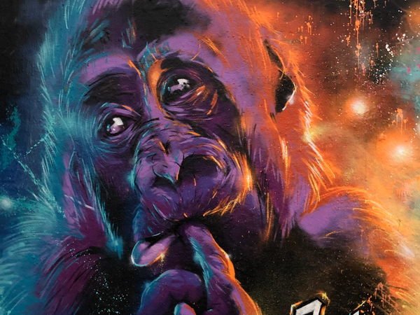 Fotorealistisk spraymålning av en fundersam apa som vilar hakan mot handen mot en lila och orange rymdbakgrund i Snösätra. Photorealistic spray paint mural of a thoughtful ape resting its chin on its hand against a purple and orange cosmic background in Snösätra.