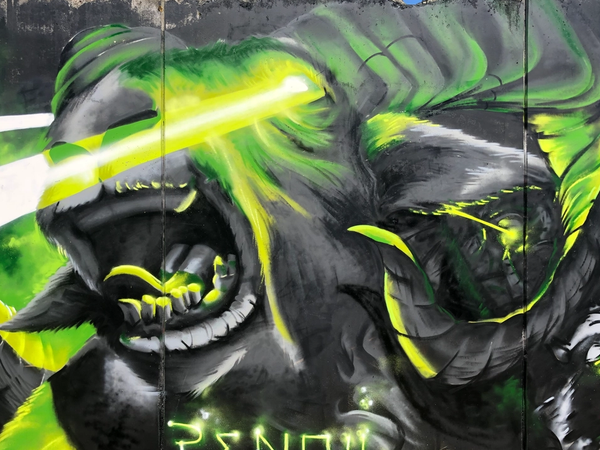 Graffitimålning av en lasergeit med lysande gröna ögon och en get-hord, slutstriden i The Raukonium Saga i Visby av Spraya. Graffiti mural of a laser goat with glowing green eyes and a goat horde, the final battle of The Raukonium Saga in Visby by Spraya.