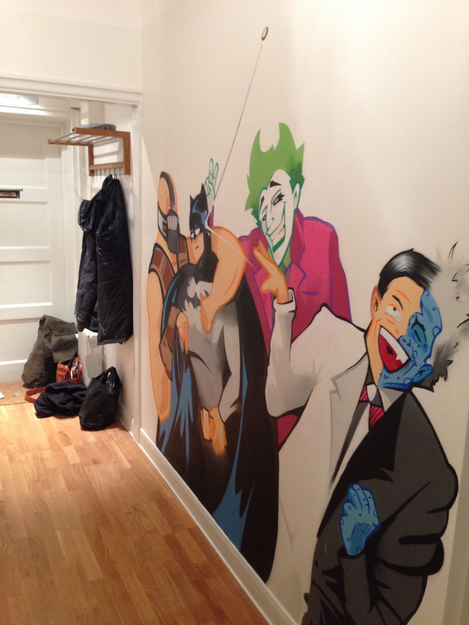 Hall i ett hem i Enskede med en seriemålning av Batmanskurkar längs väggen. Home hallway in Enskede with a comic mural of Batman villains painted along the wall.