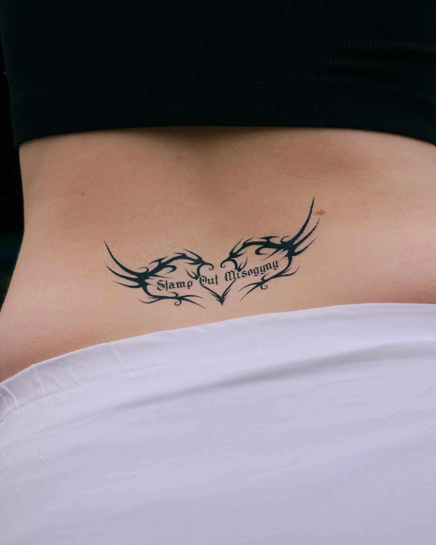 Temporary tattoo placed on a woman's lower back that reads 'Stamp Out Misogyny'