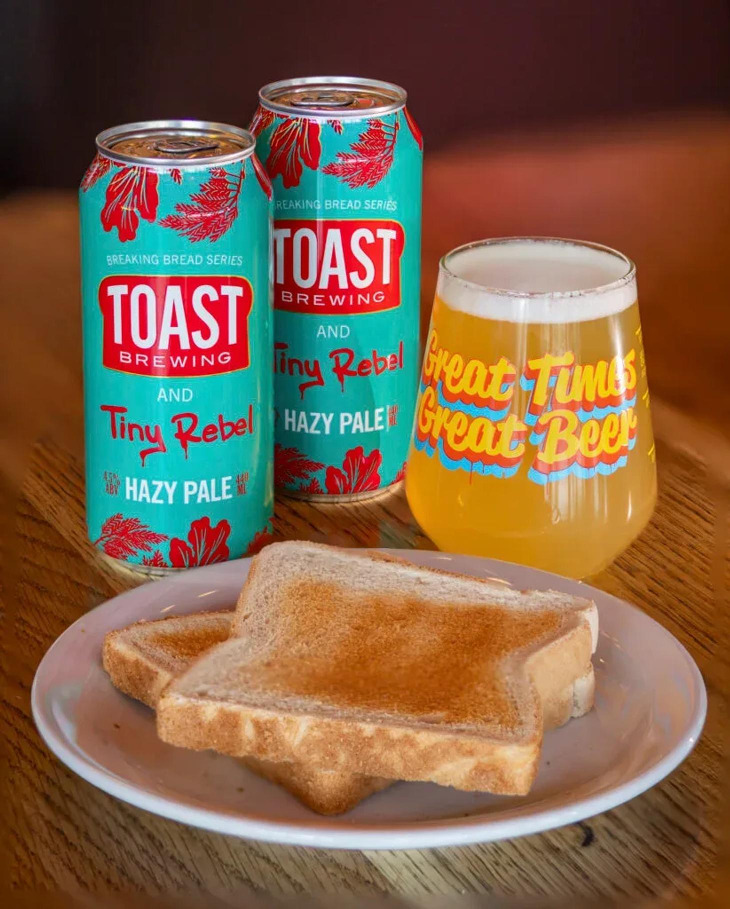 Toast Brewing and Tiny Rebel Breaking Bread cans beside a poured pale ale and toast on a plate