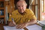 Yvon Chouinard, founder of the brand Patagonia wearing a yellow check shirt signing documents