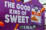 Close, angled view of the Strong Roots mural by Don’t Panic London, showing oversized “The Good Kind of Sweet” lettering, a pack of crispy sweet potato fries and the line “Let’s Be Real.”
