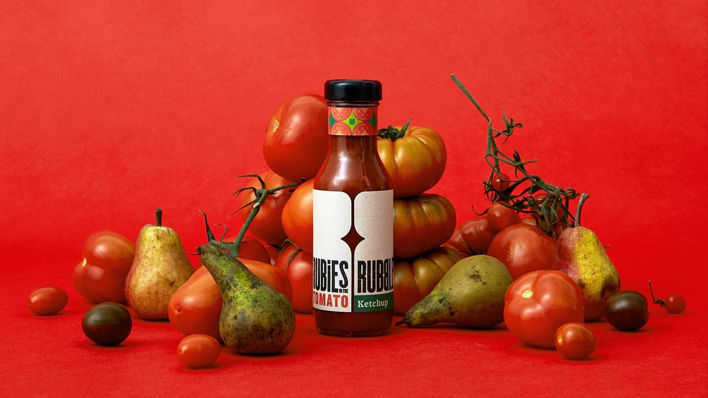 A bottle of Rubies tomato ketchup surrounded by fresh ingredients of tomatoes and pears