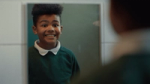 Still from Don't Panic London's Brave Face film for Shelter: a boy in a school jumper puts on a big grin in the mirror