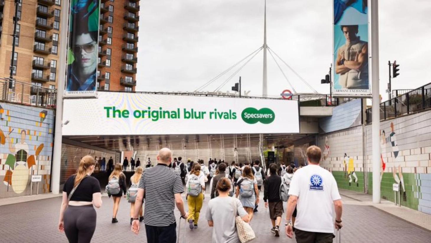 Specsavers 'The original blur rivals' billboard above crowds at Wembley Park for Oasis