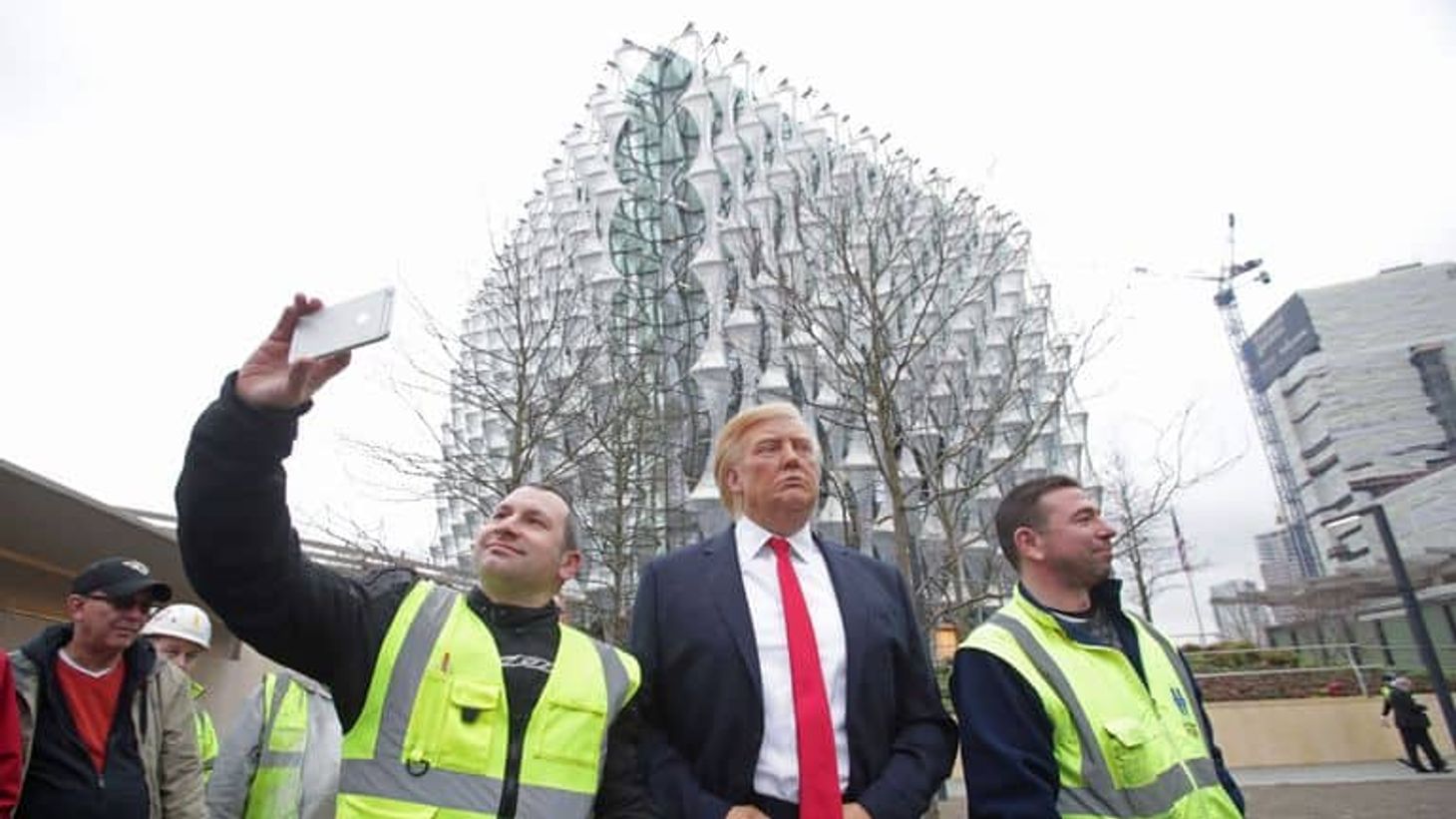 Donald Trump walking with men wearing high vis vests and taking selfies